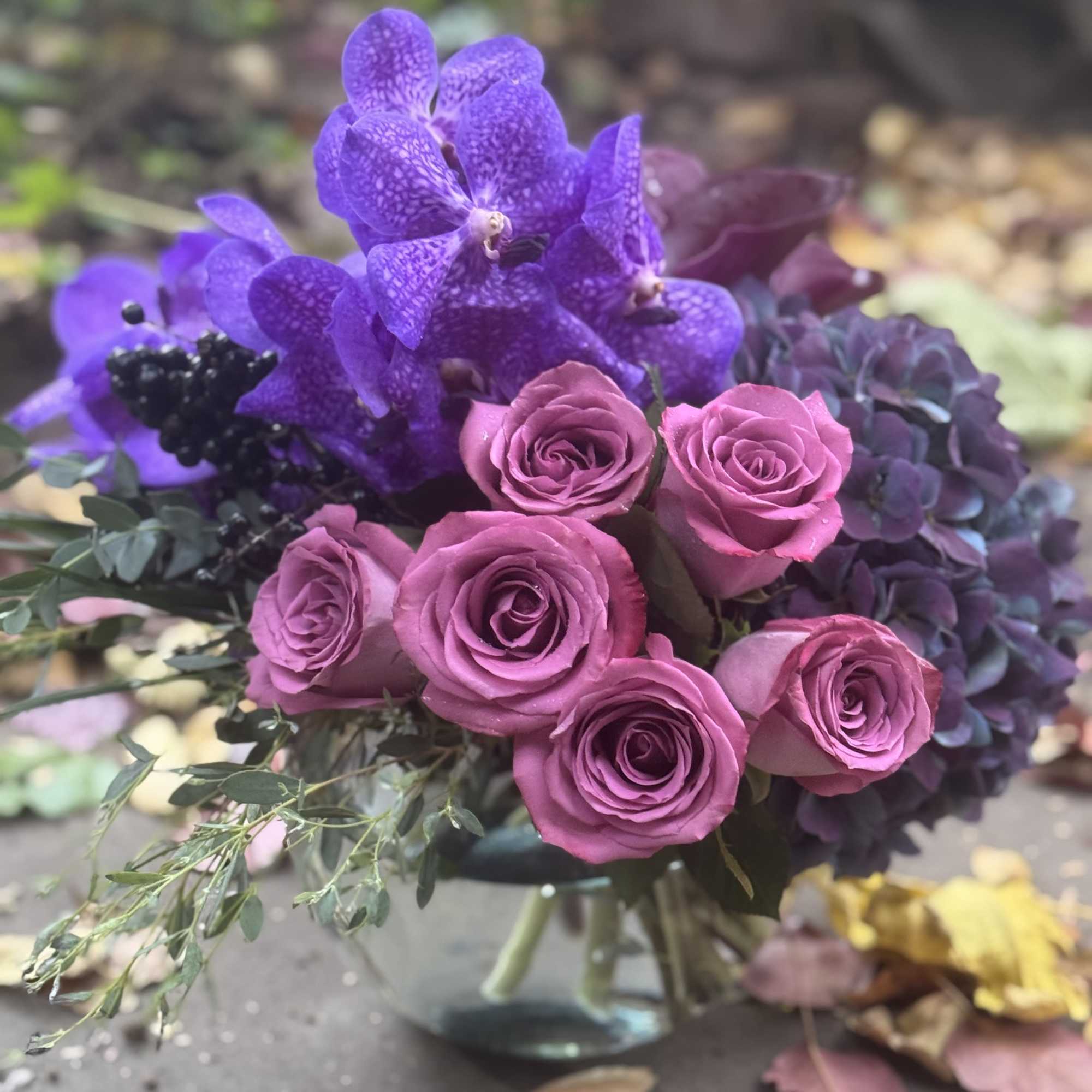 Purple orchids and pink roses arranged in a glass vase, photo 2 of 2