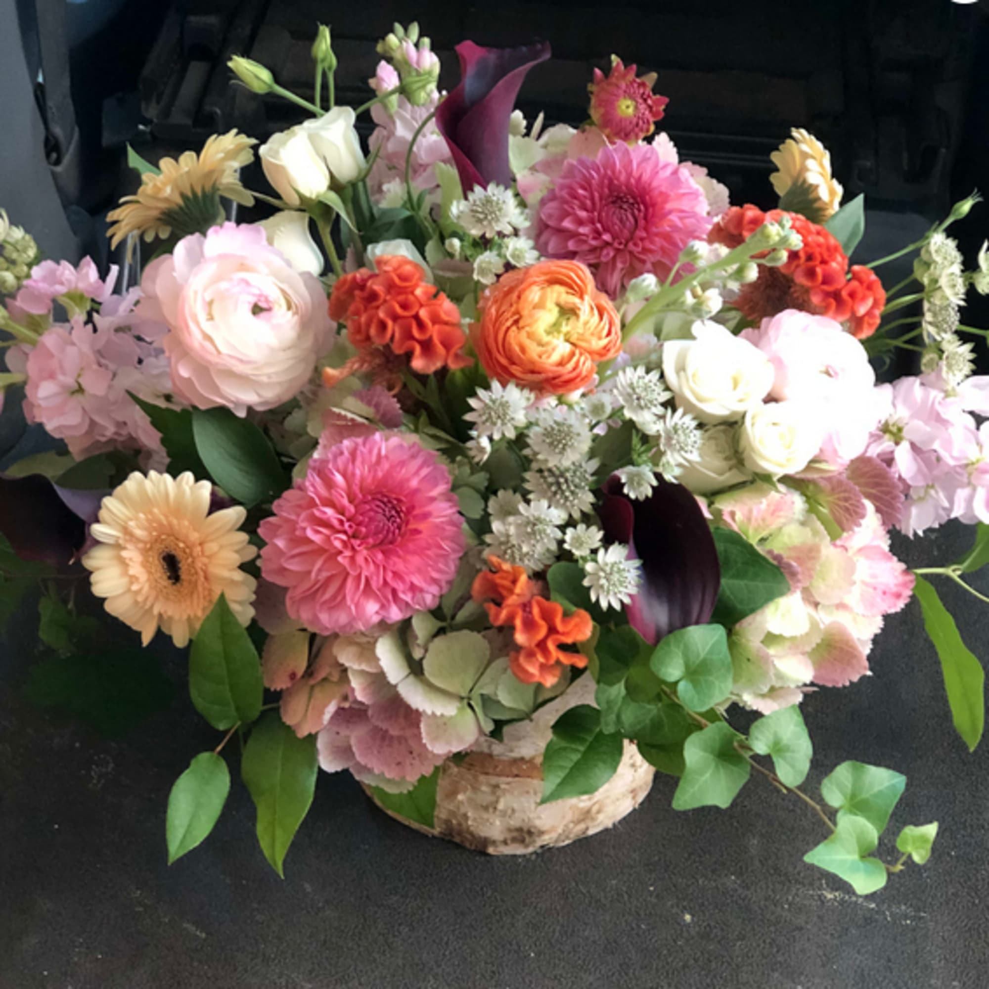 Mixed bouquet in a birch container with pink, white, orange, and purple flowers