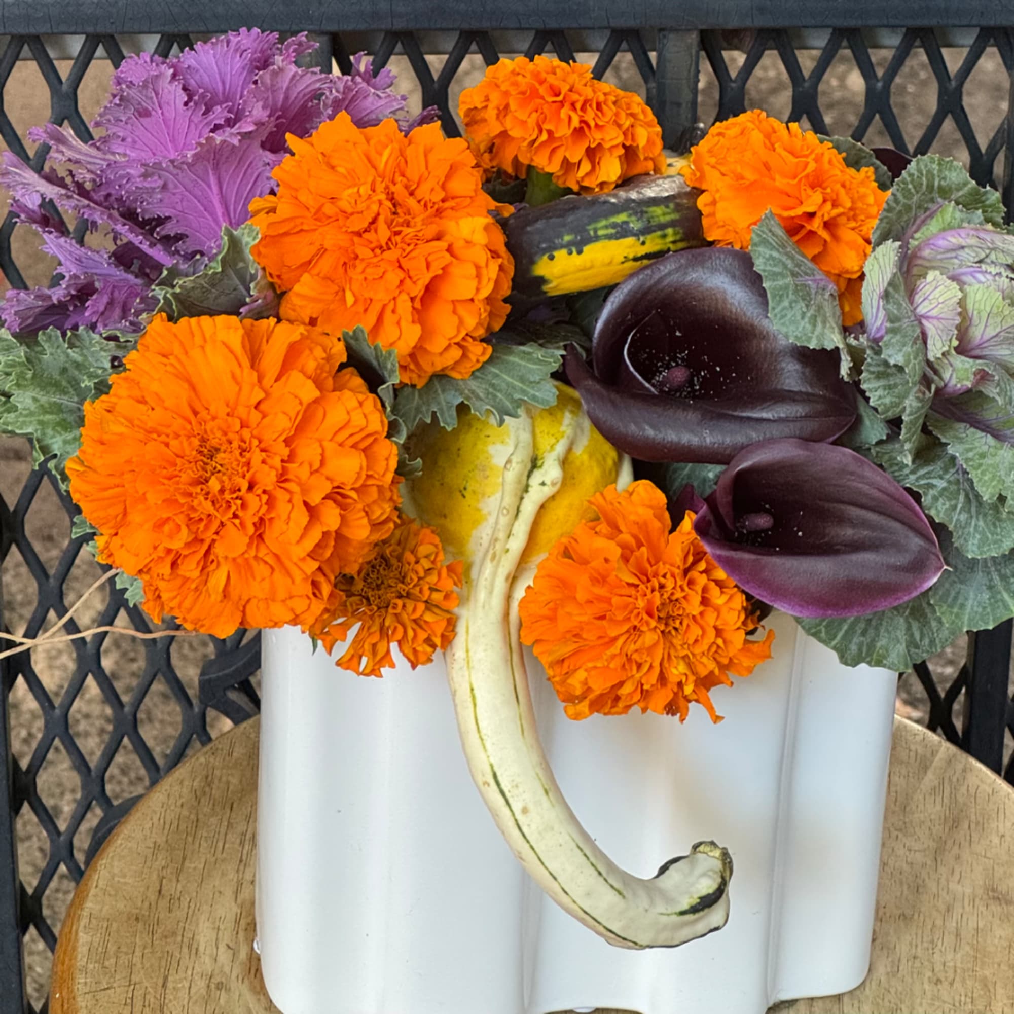 Orange marigolds and dark calla lilies in a white pumpkin vase