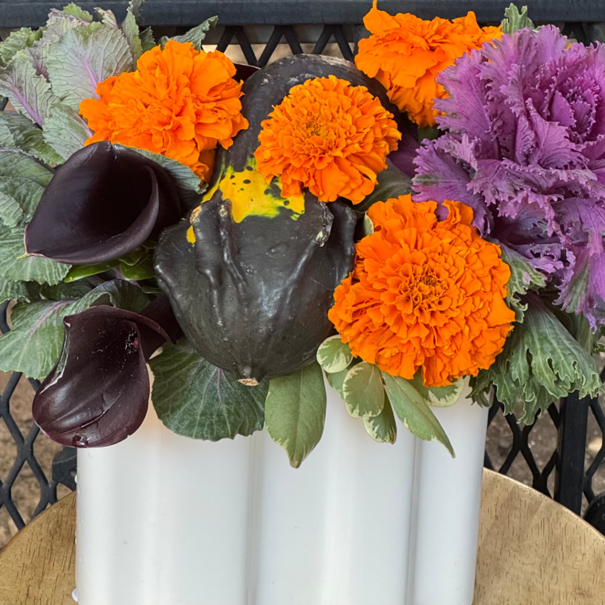 Orange marigolds and purple ornamental cabbage in a white container