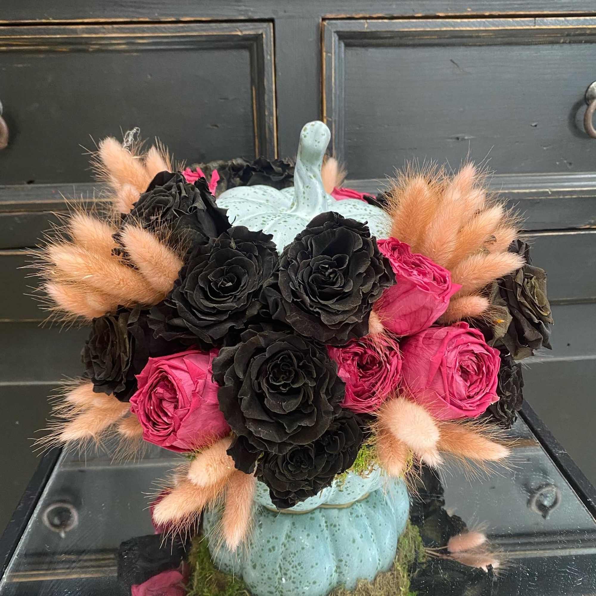 An enchanting ceramic pumpkin beautifully arranged with preserved black roses, mauve garden