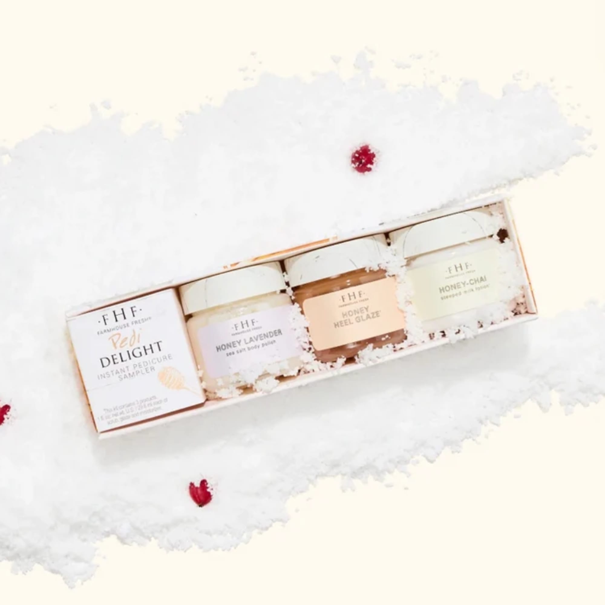 Gift set with four skincare jars in a white box on a fluffy white surface