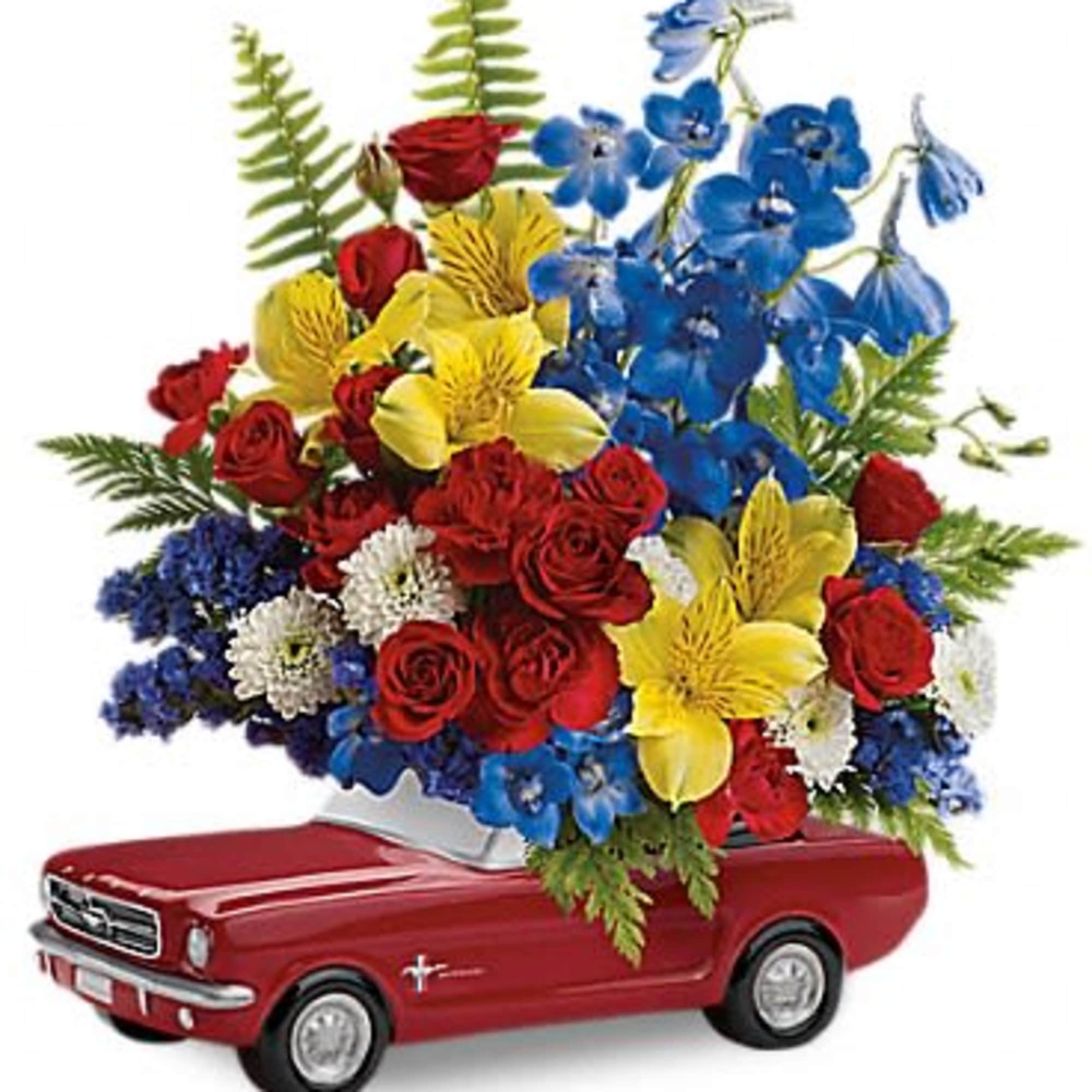 Red, yellow, and blue flower arrangement in a red toy car