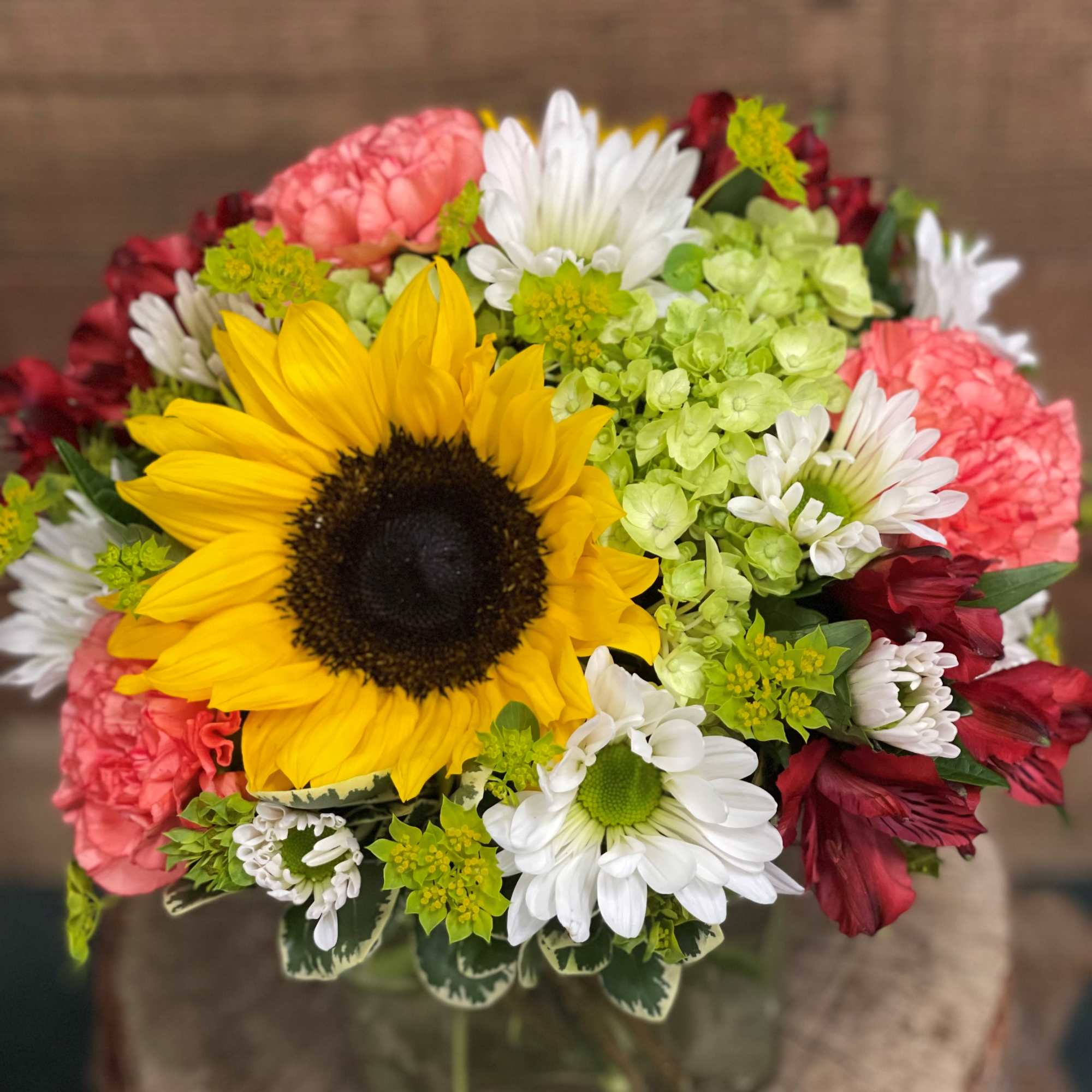 Sunny sunflowers artfully paired with bright and summery long lasting flowers. Nestled