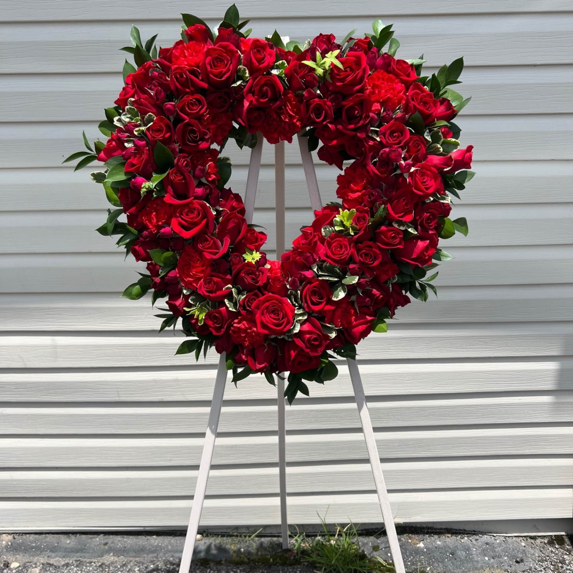 Heart-shaped red rose wreath on a standing easel