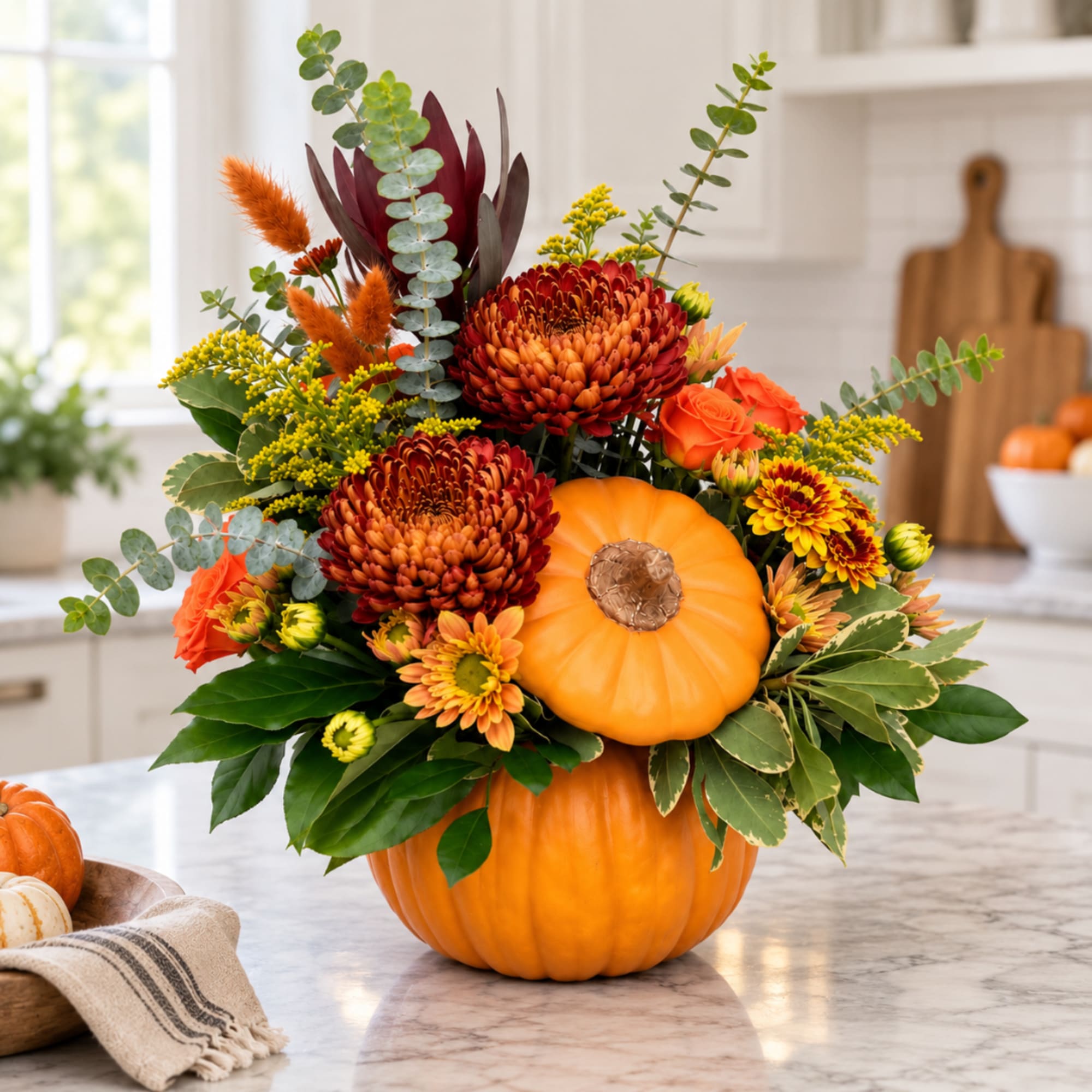 Fall floral arrangement in stacked pumpkins with orange and burgundy blooms