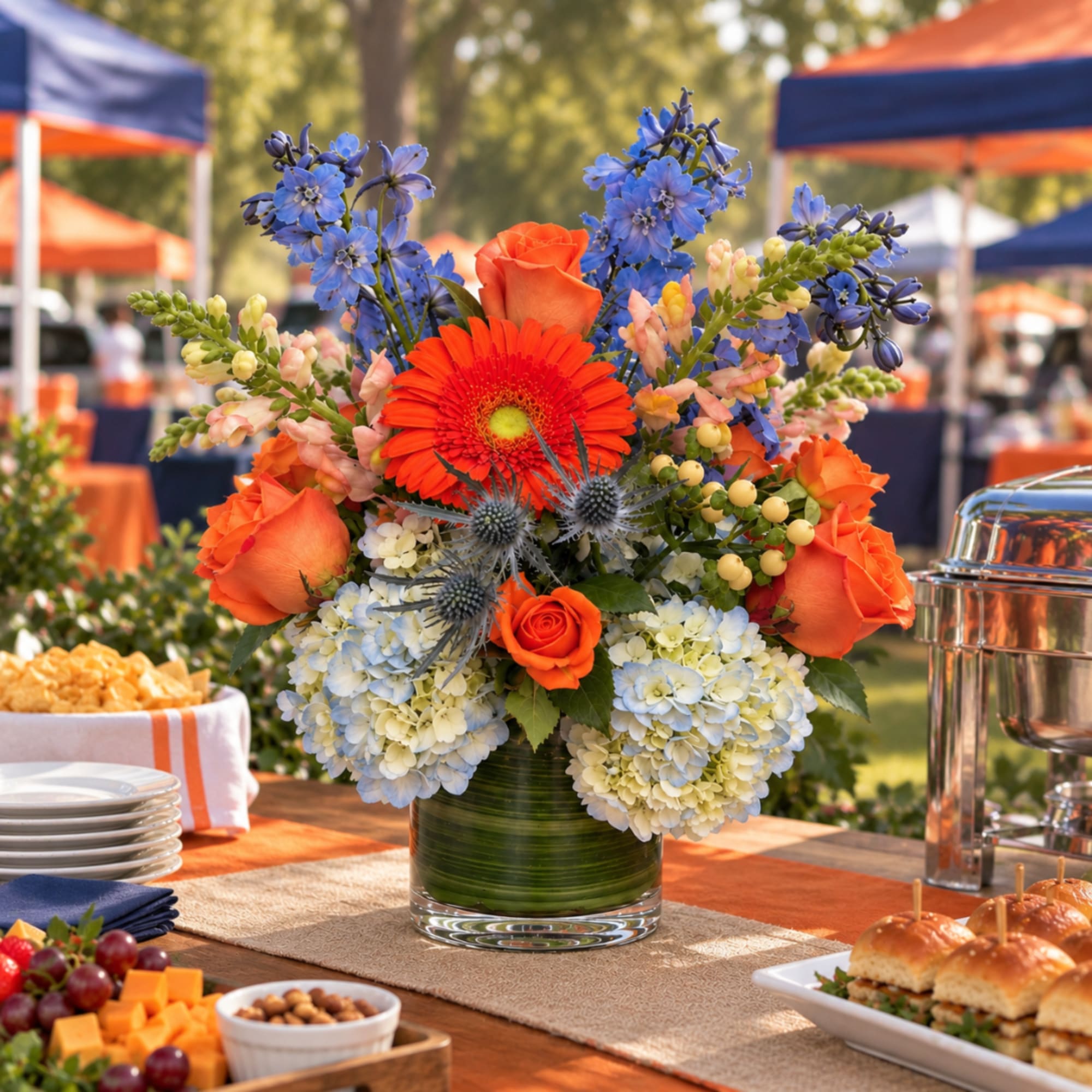 Orange and blue mixed flower arrangement in a glass vase on a table