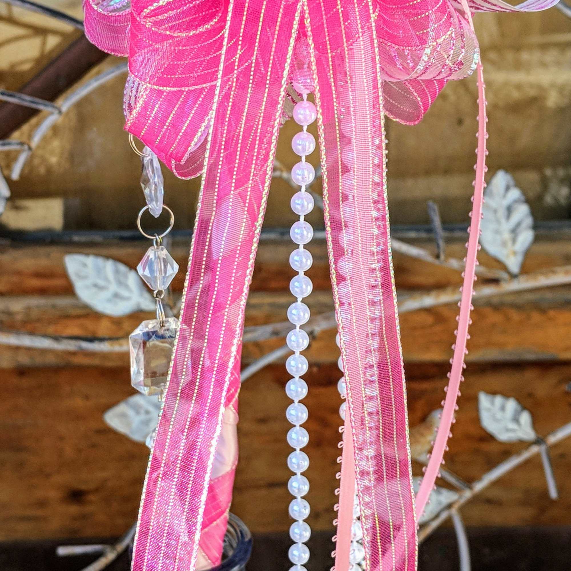 Single pale rose with large pink bow, pearls, and crystals displayed in a small pink glass bud vase