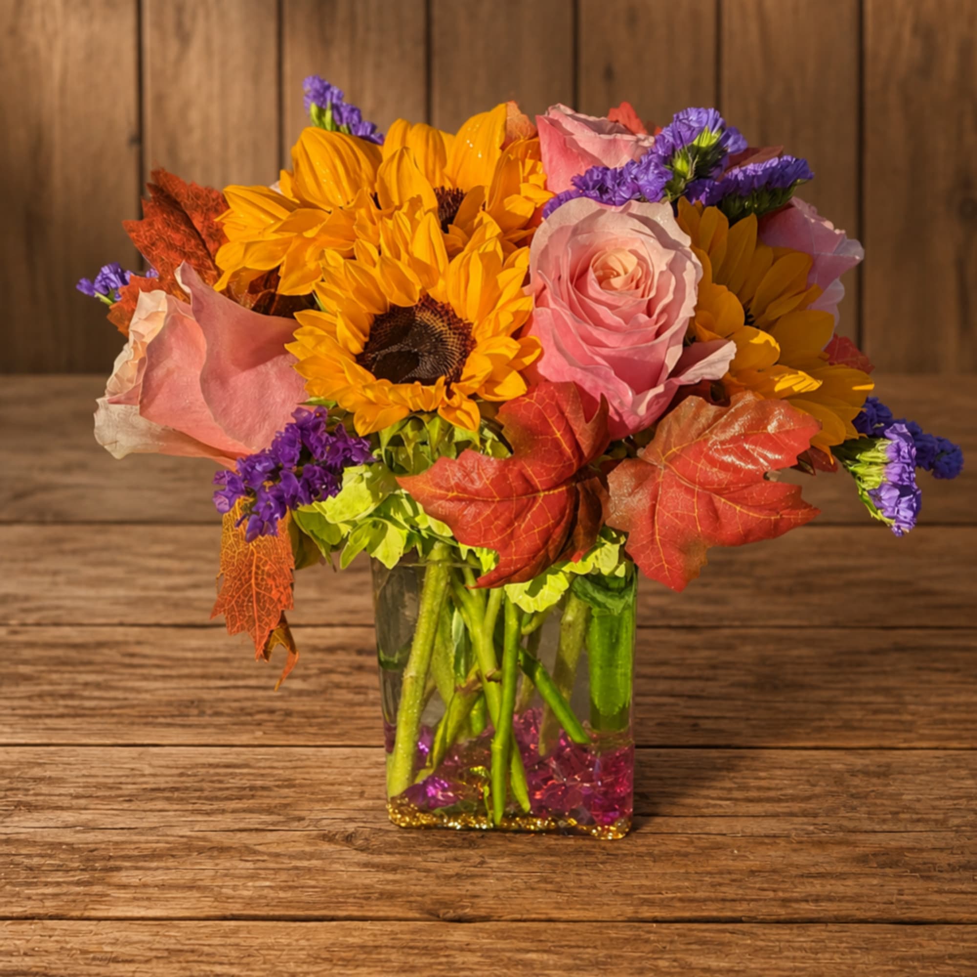 Bouquet of sunflowers and pink roses in a clear square vase