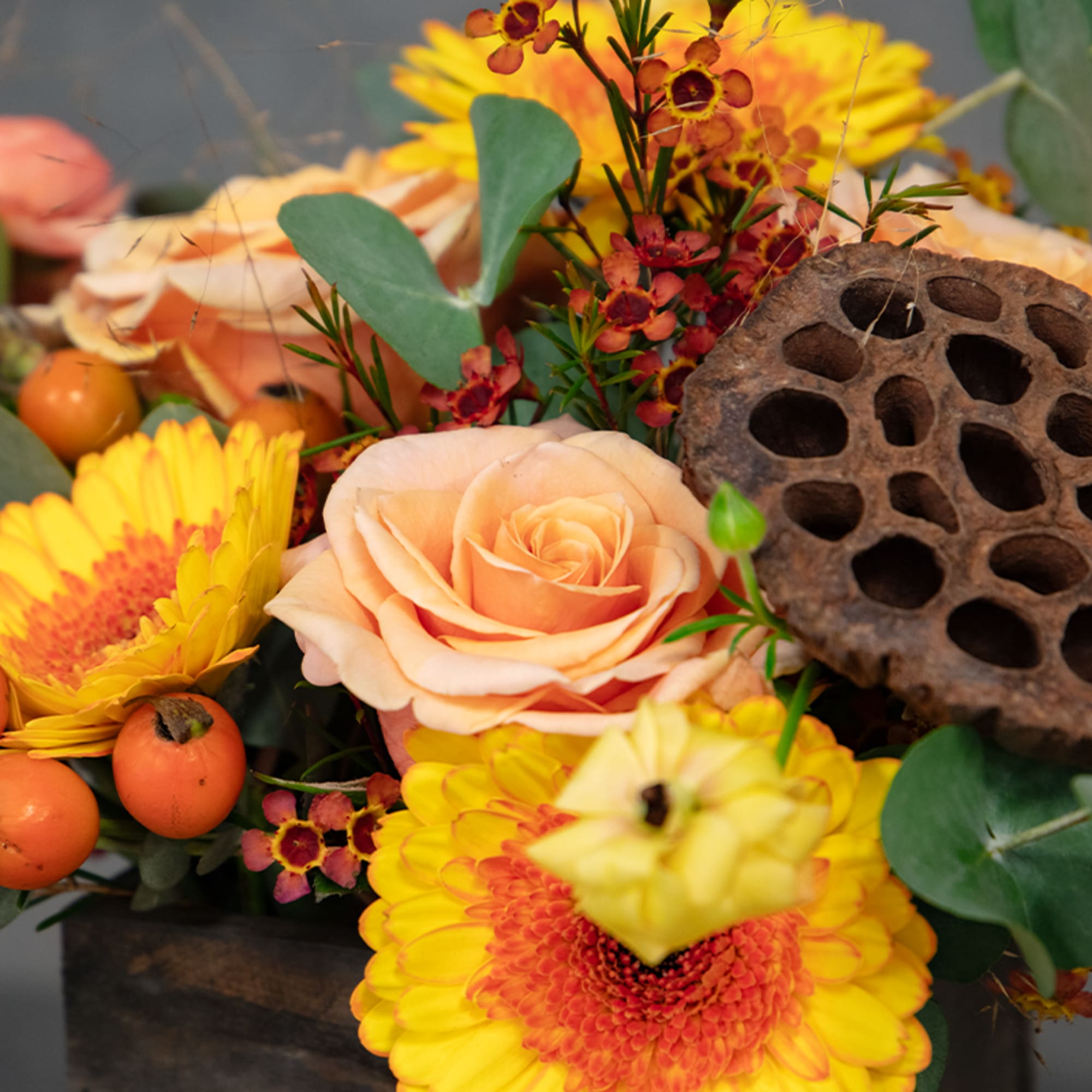 Peach roses and yellow gerbera daisies in a dark container