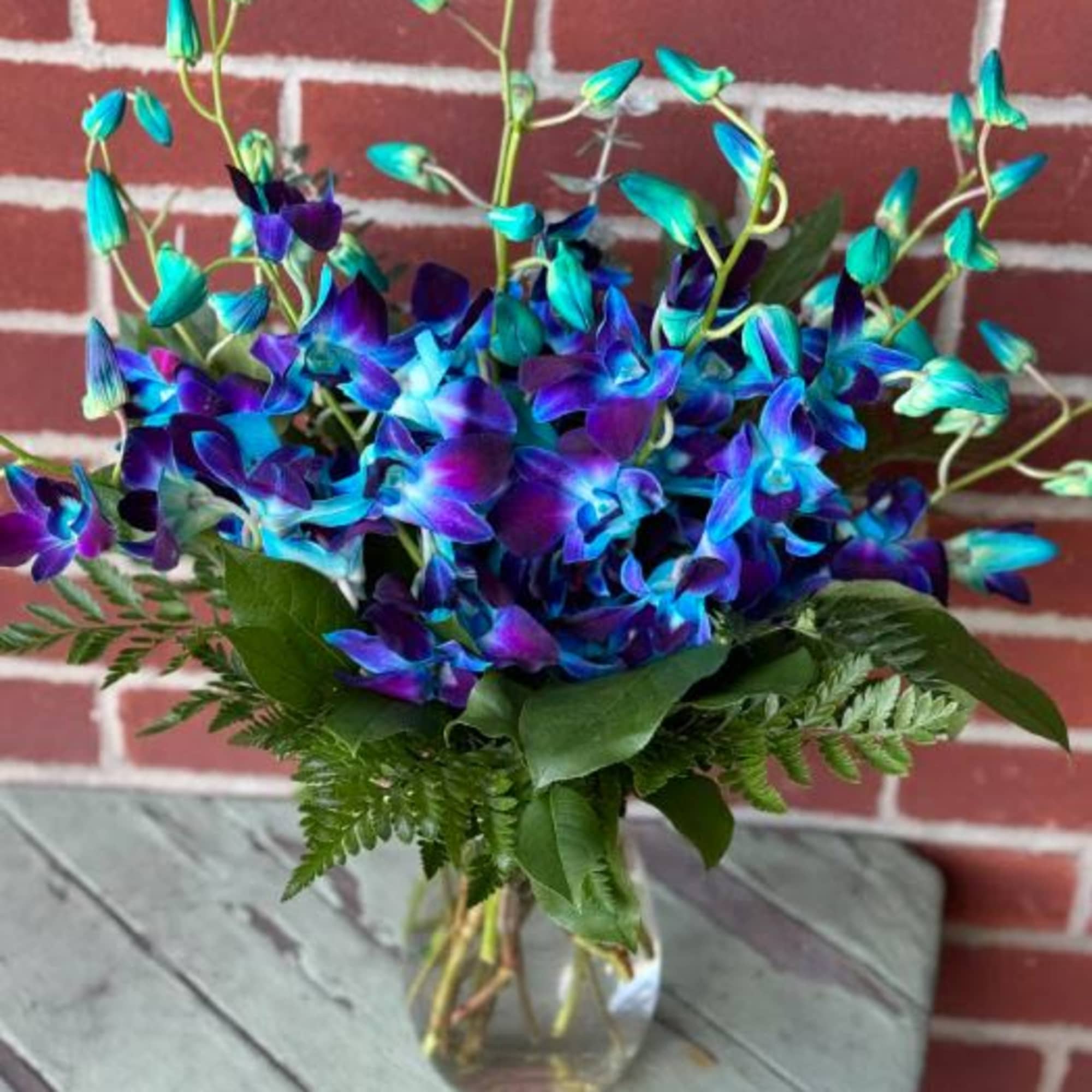 Blue and purple orchid arrangement in a clear glass vase