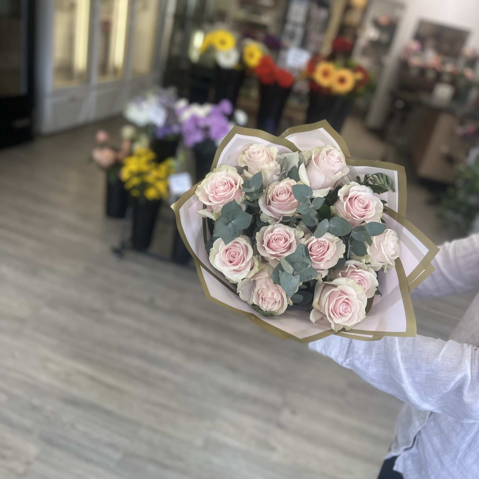 Handheld bouquet of pale pink roses wrapped in paper