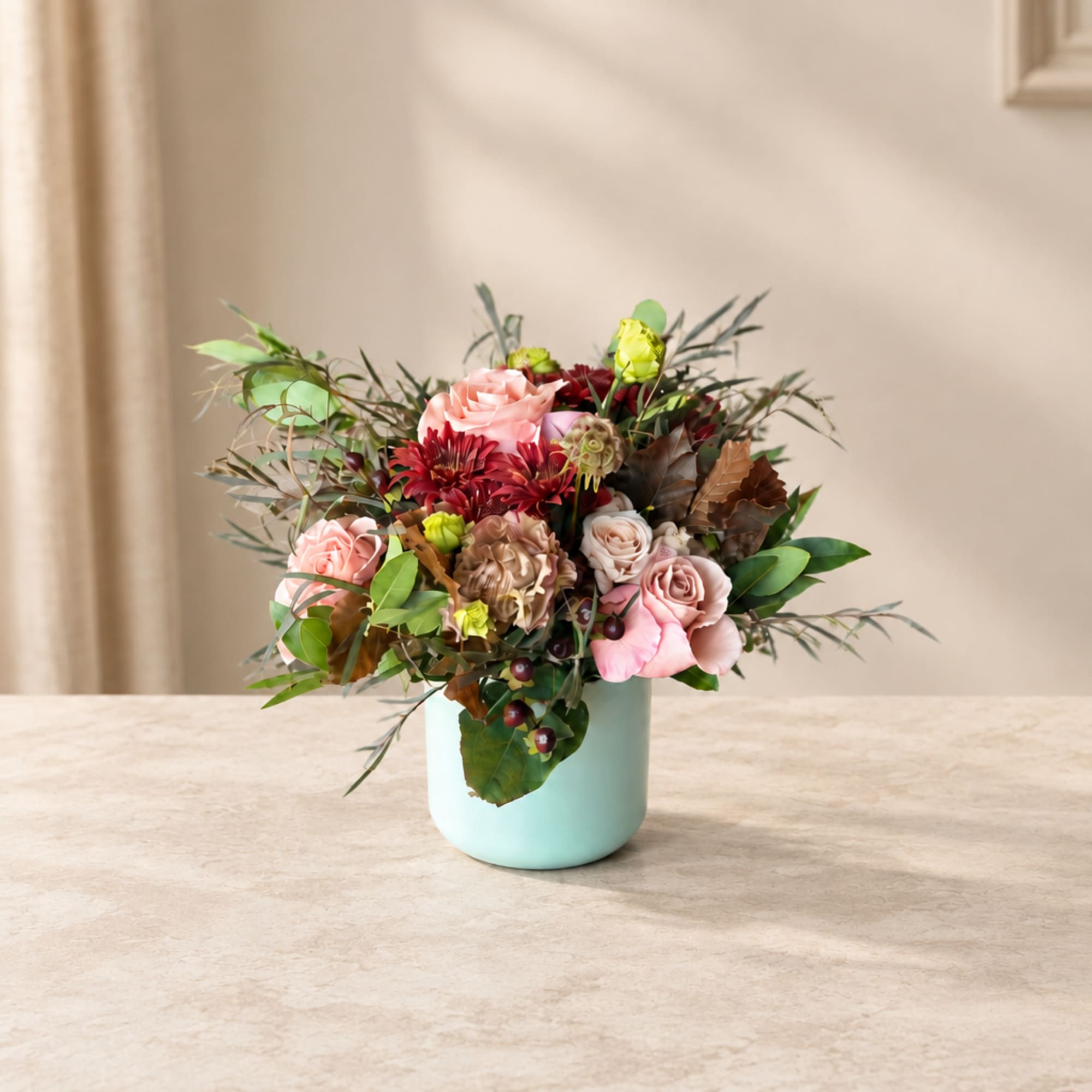 Pink and red floral arrangement in a light blue vase