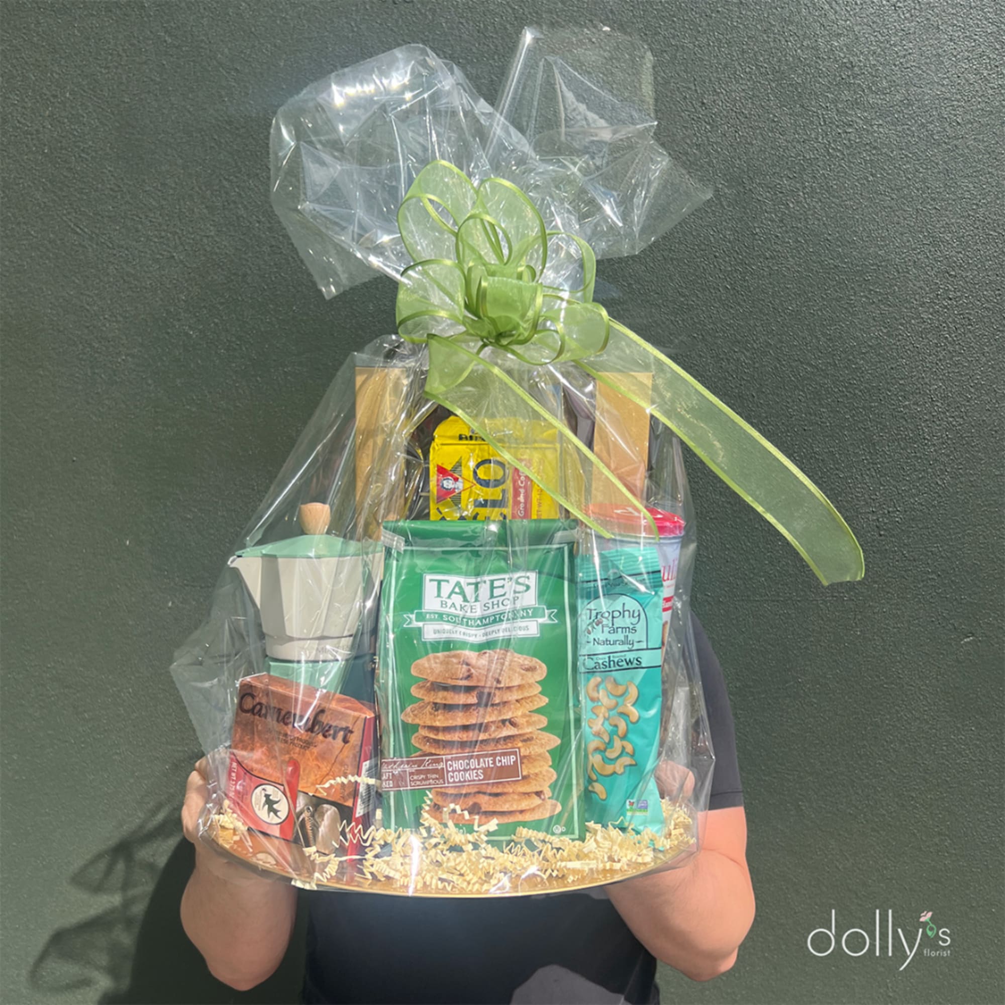 Gift basket of snacks wrapped in clear cellophane with a green bow
