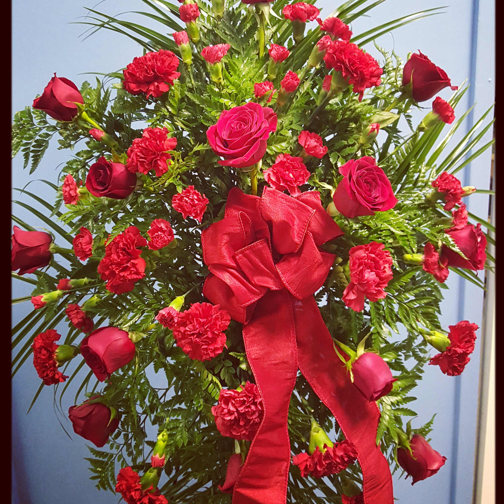 Red roses and carnations arranged with a large red ribbon