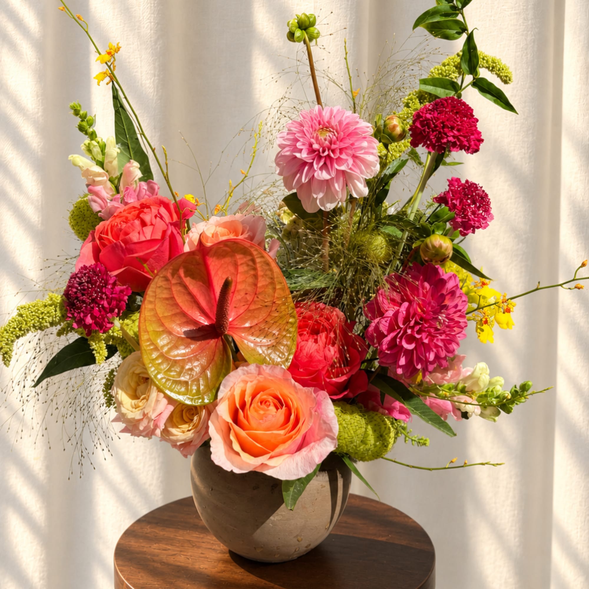 Colorful mixed bouquet in a round vase with roses, dahlias, and anthurium
