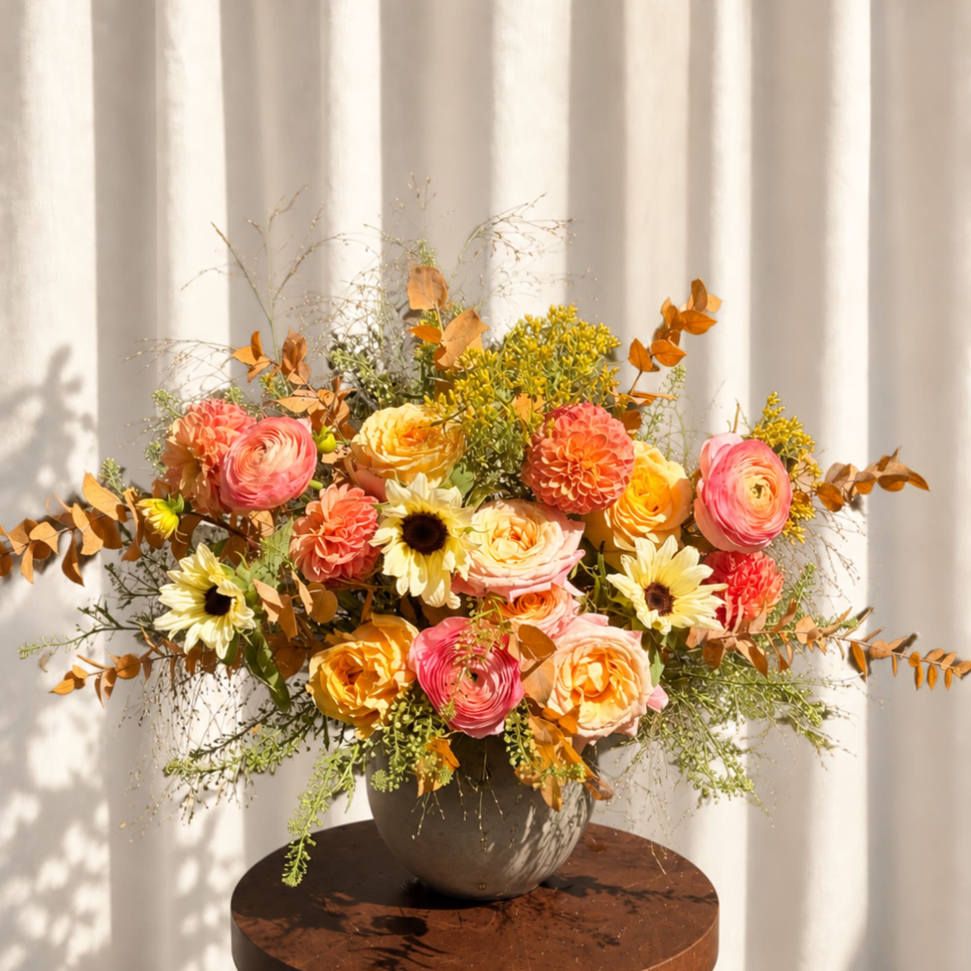 Colorful floral arrangement in a round vase with pink, peach, yellow, and orange blooms