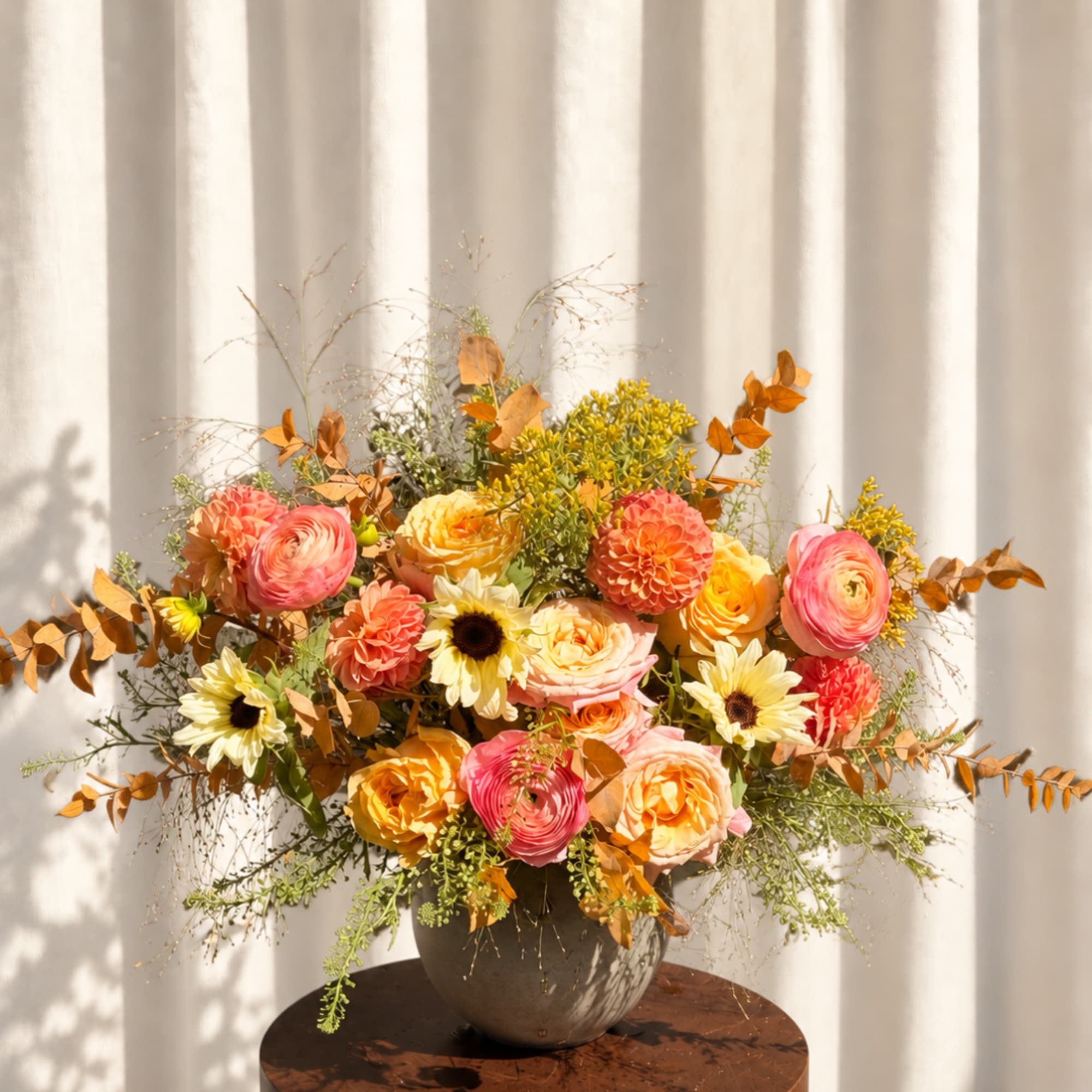 Colorful bouquet of ranunculus and sunflowers in a dark vase