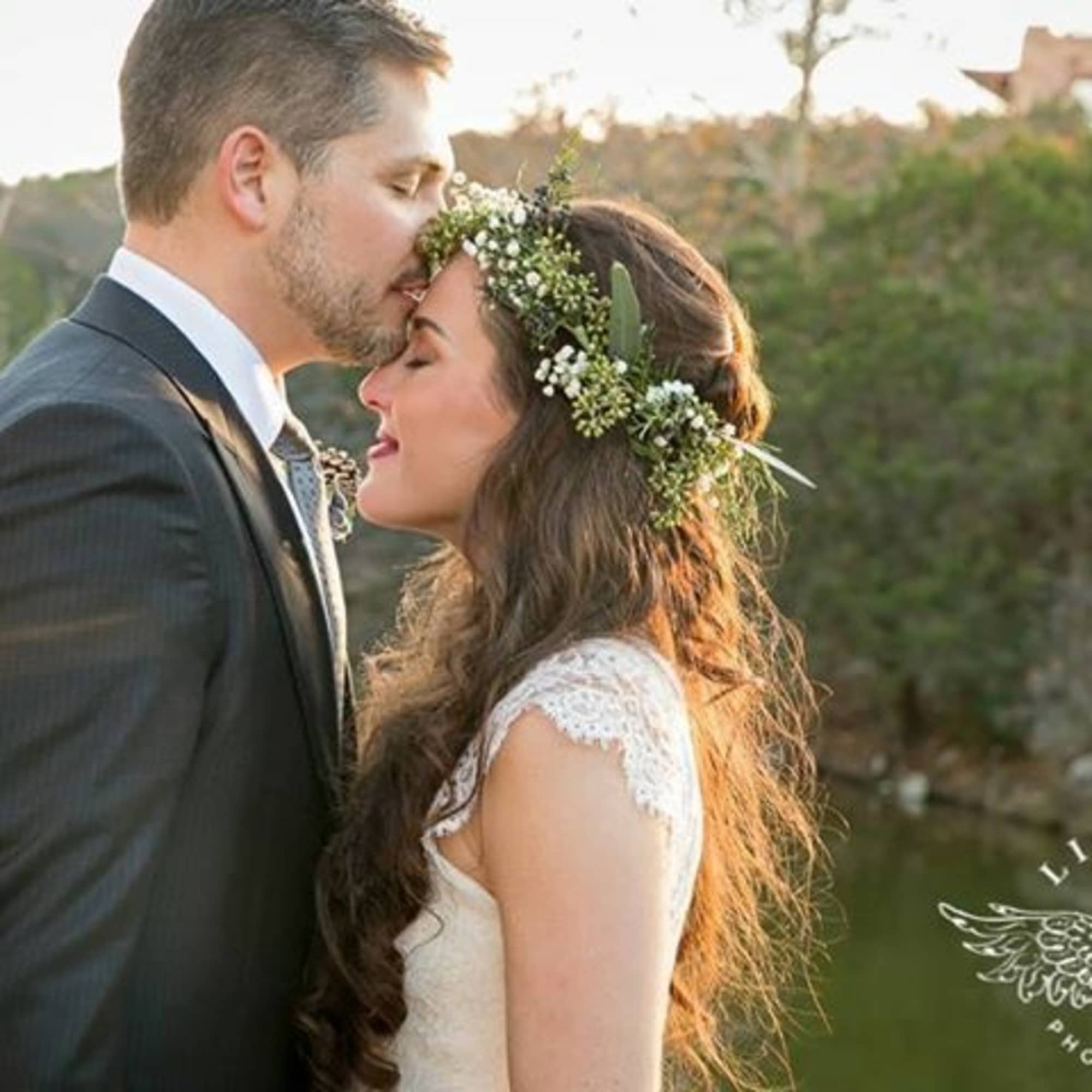 Bride and groom in an outdoor kiss, with a floral crown on the bride