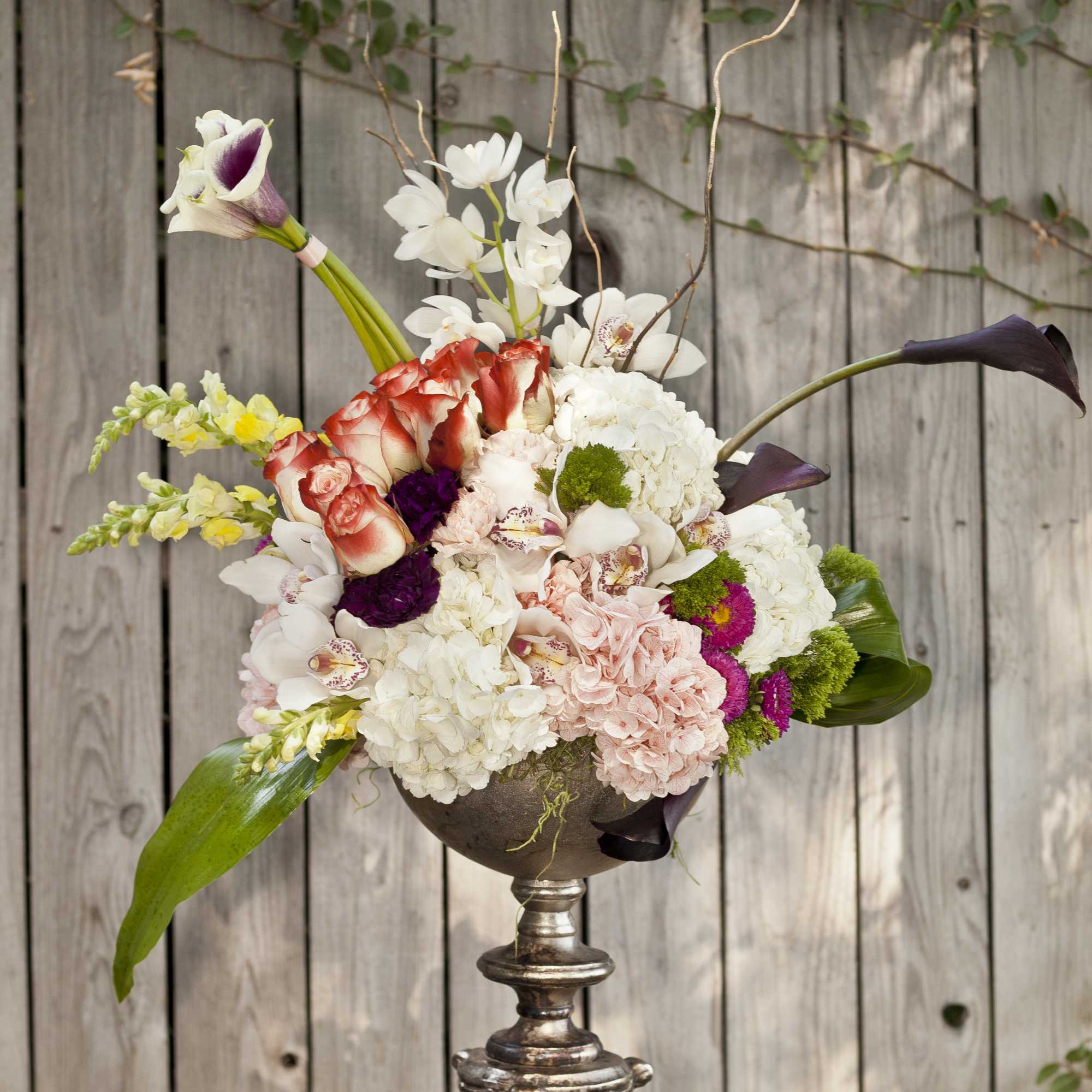Mixed floral arrangement in a silver pedestal vase with white, pink, and purple blooms