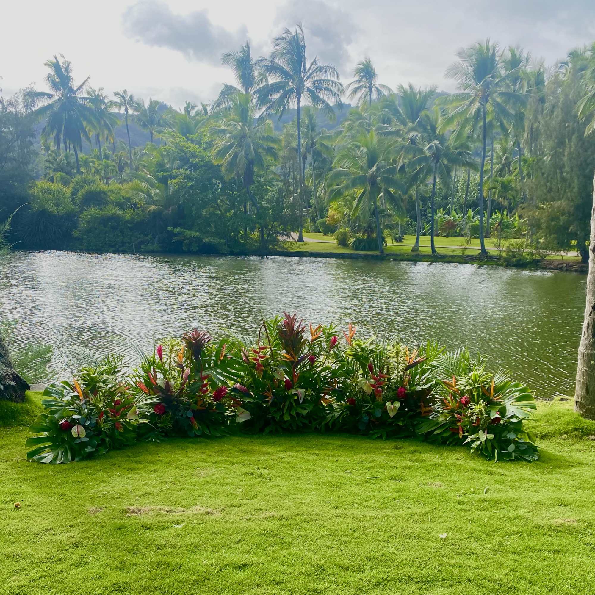Tropical floral arrangement on a lawn beside a pond
