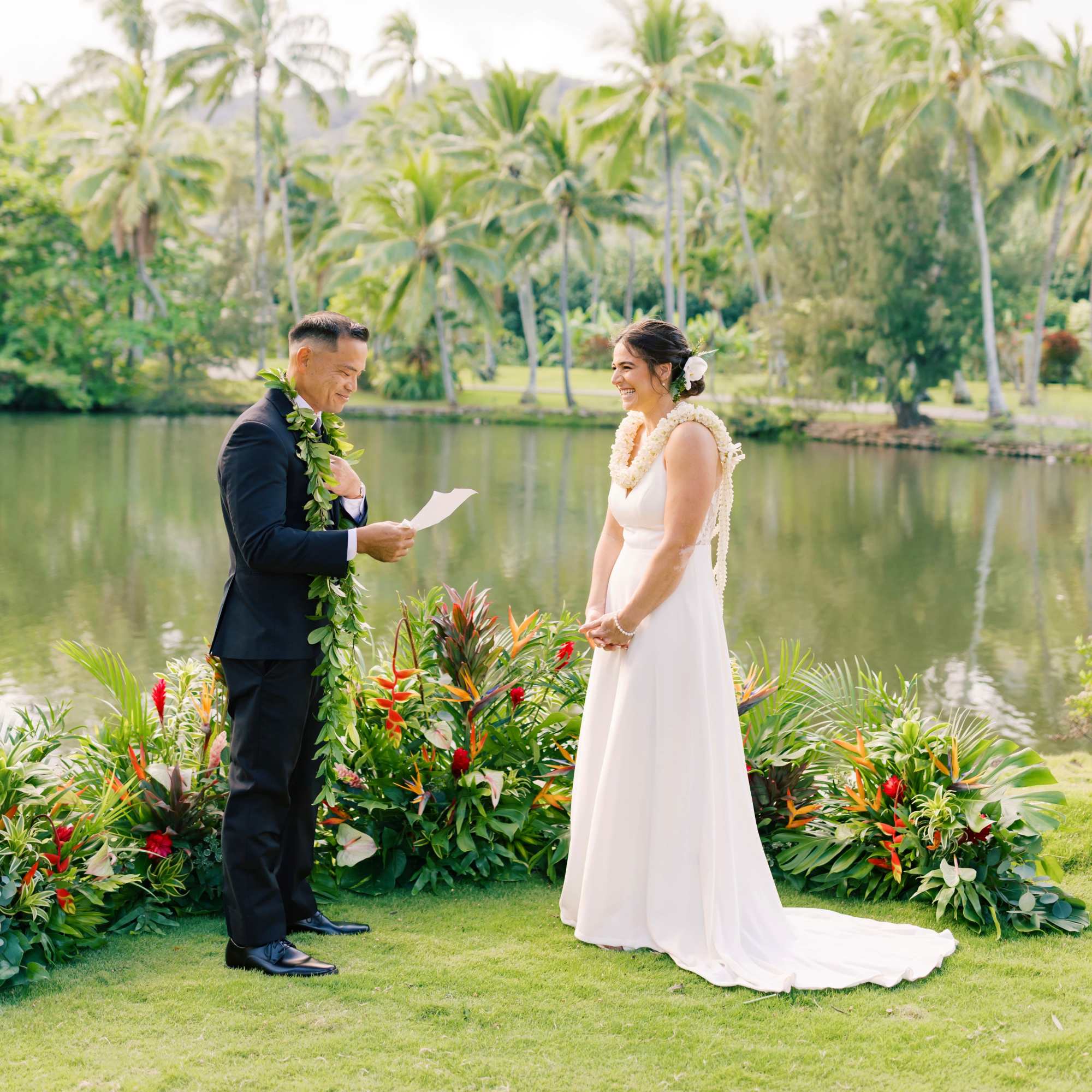 Bride and groom standing by tropical floral arrangements during a wedding ceremony