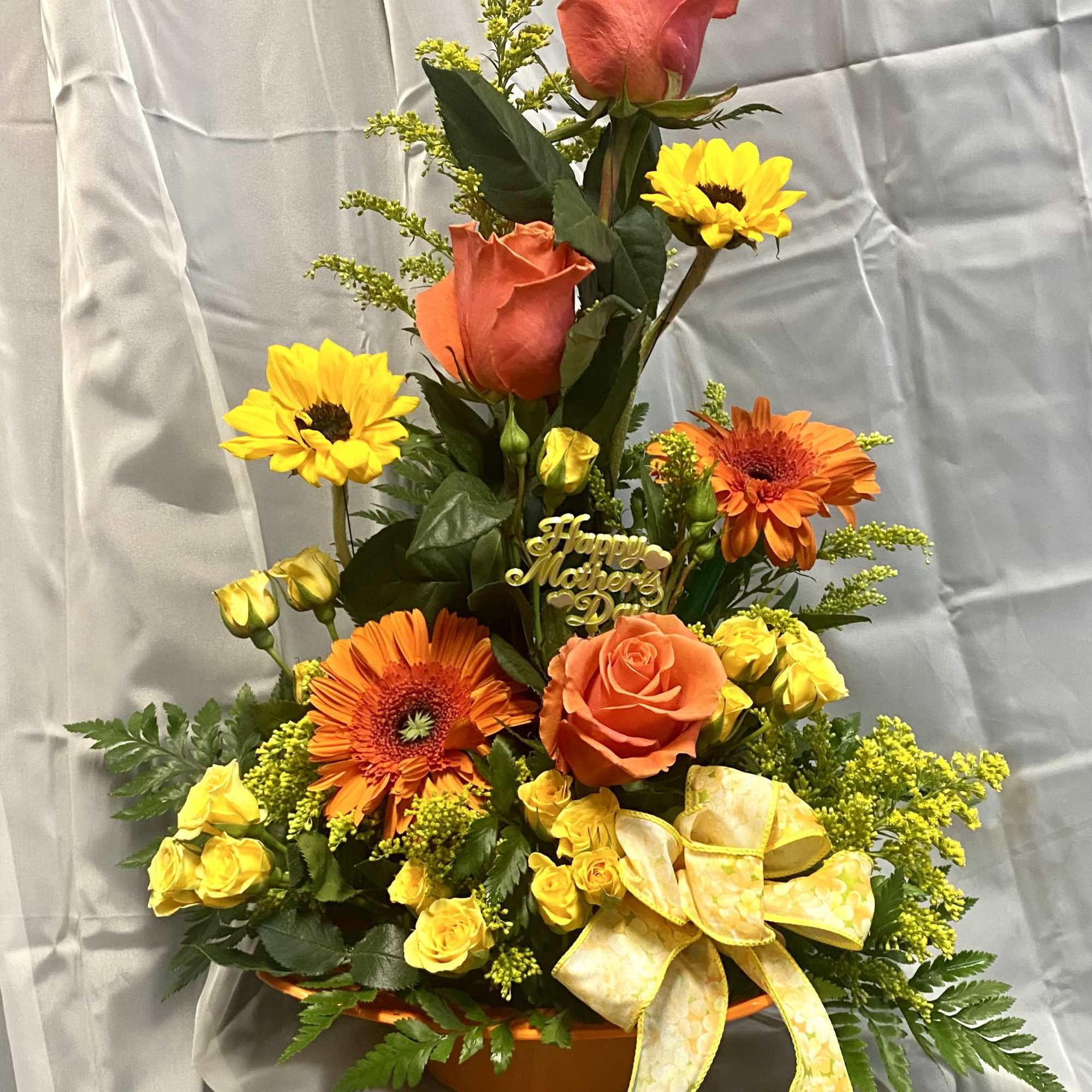 Orange and yellow floral arrangement with roses and gerbera daisies in a basket