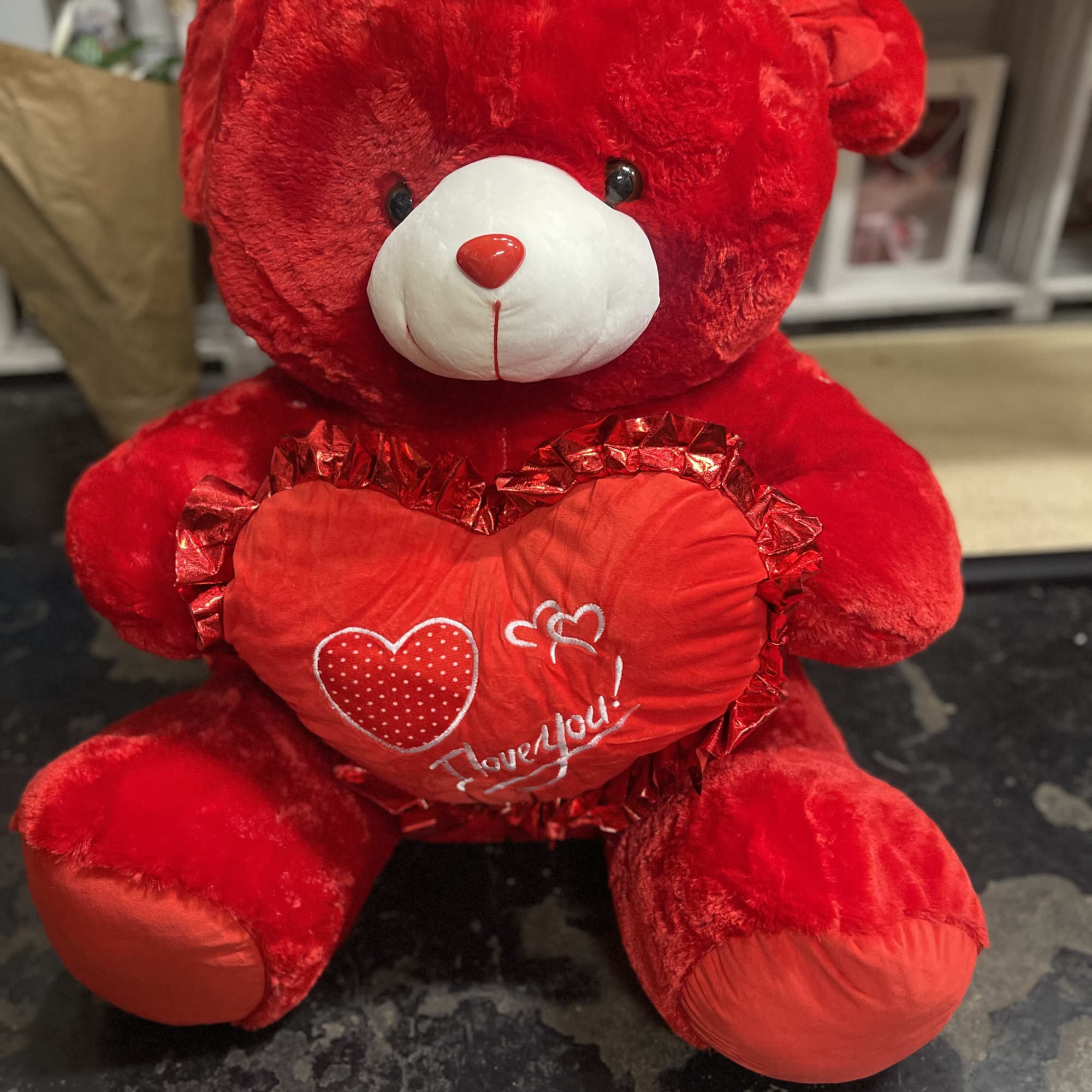 Red teddy bear holding a heart-shaped pillow