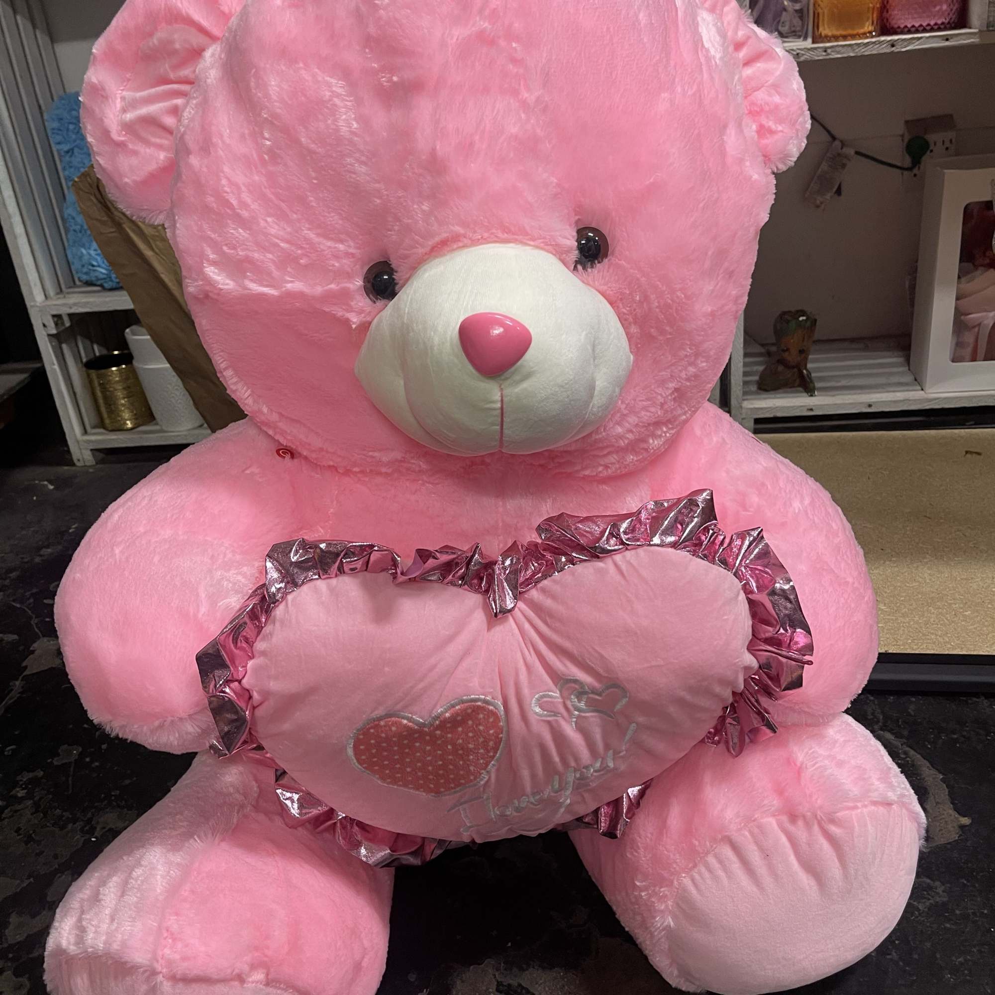Large pink teddy bear holding a heart-shaped pillow