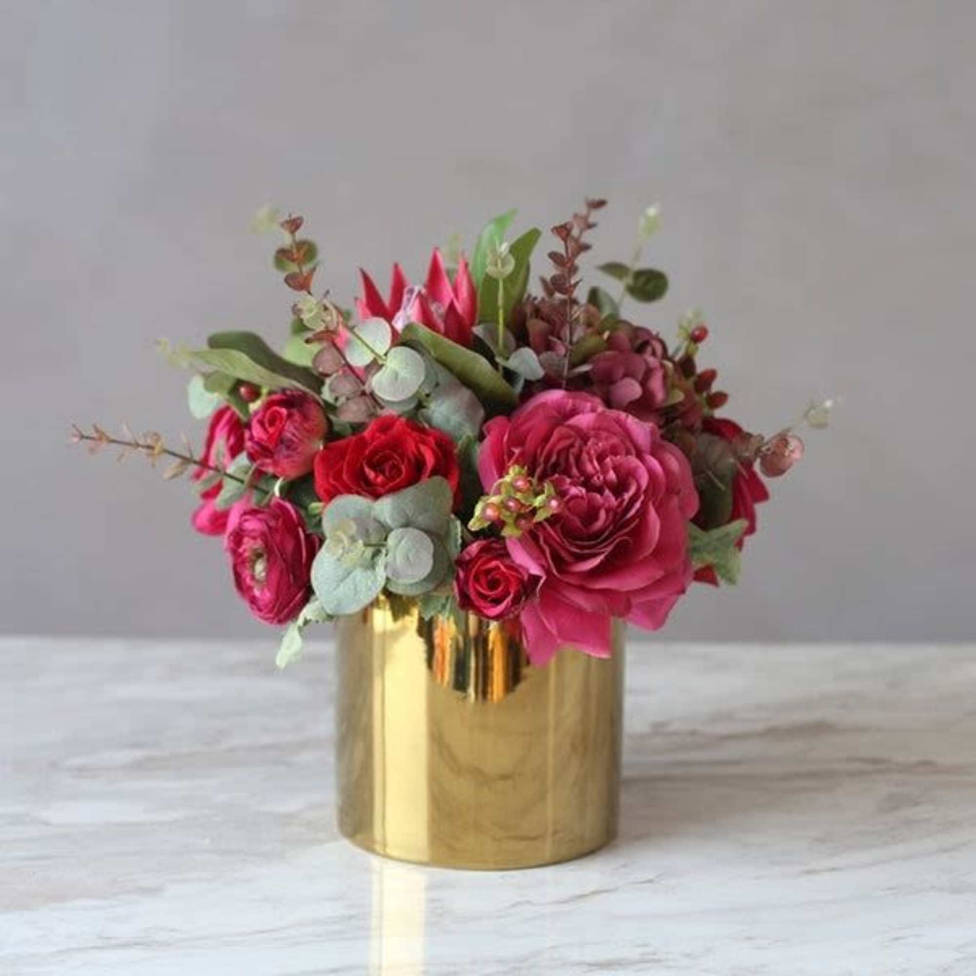 Pink and red roses arranged in a gold vase