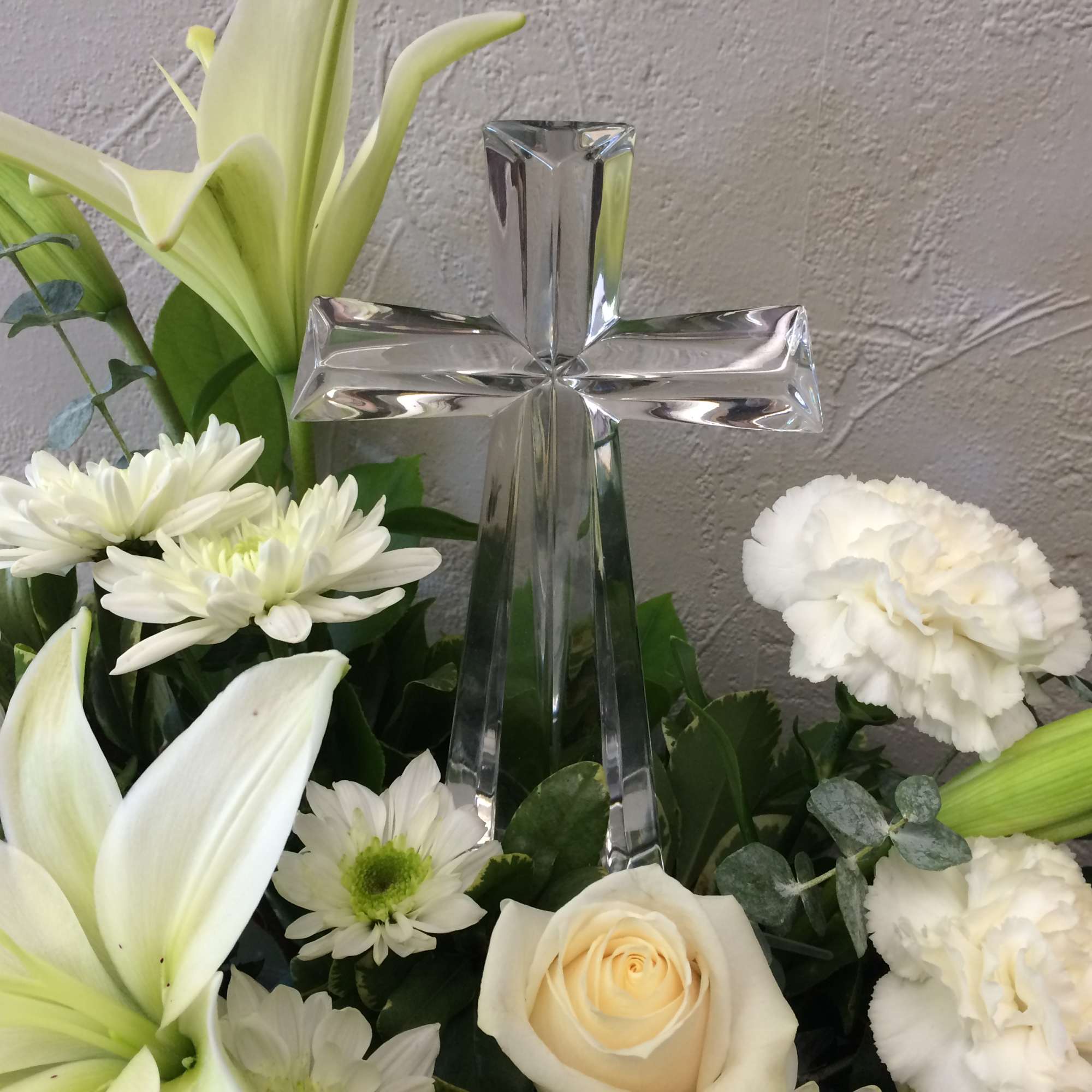 White floral arrangement with a clear glass cross centerpiece