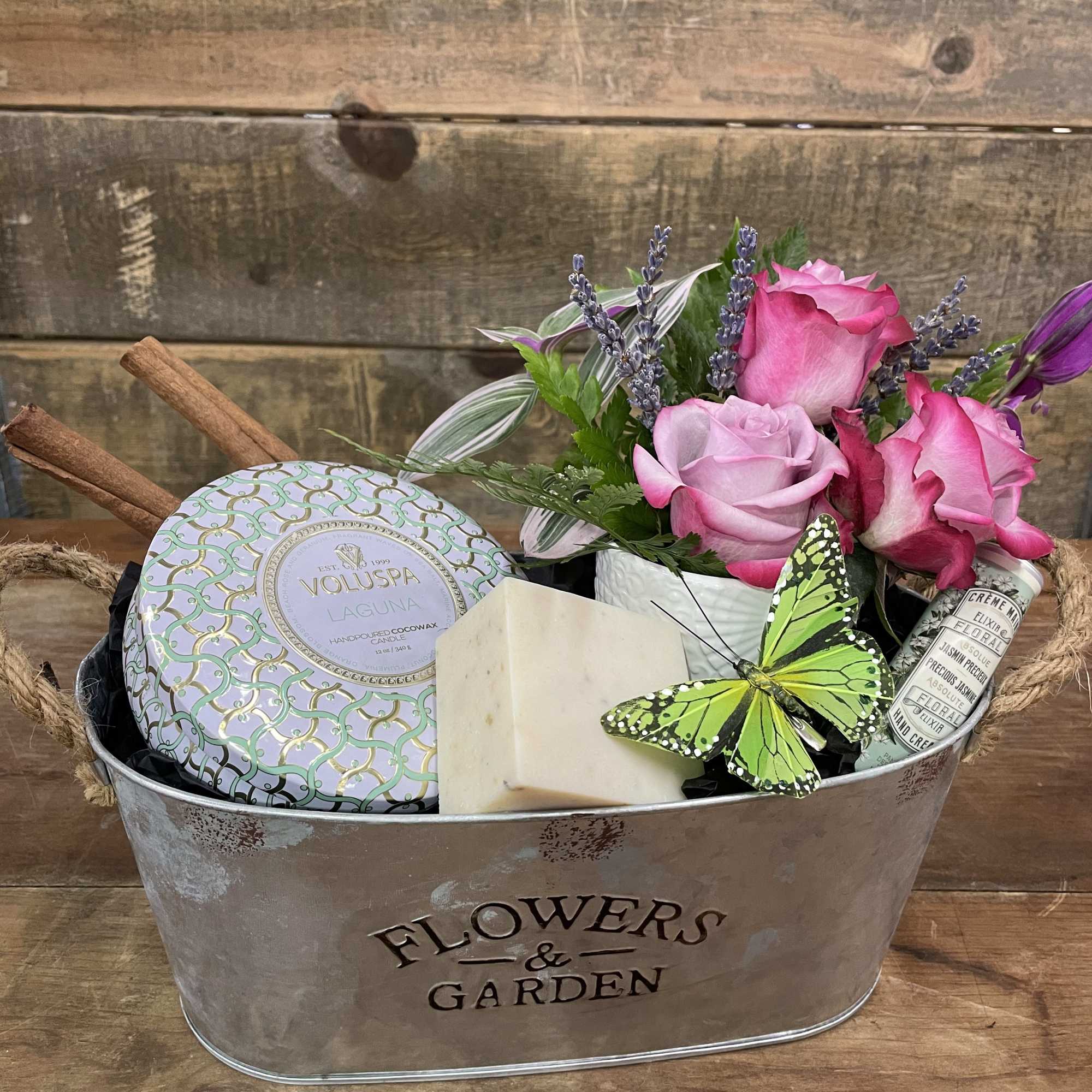 Gift basket with pink roses, a candle tin, soap, and a butterfly decoration