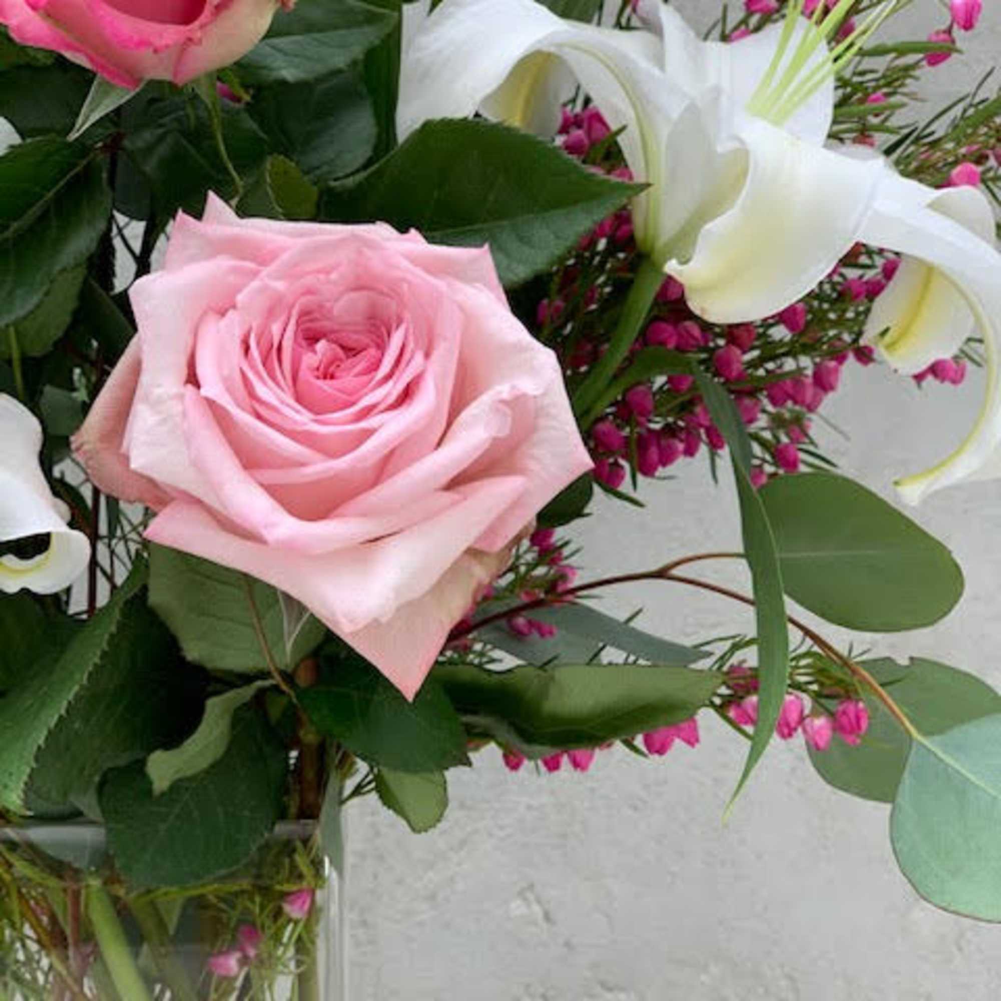 Pink and white roses with white lilies in a glass vase