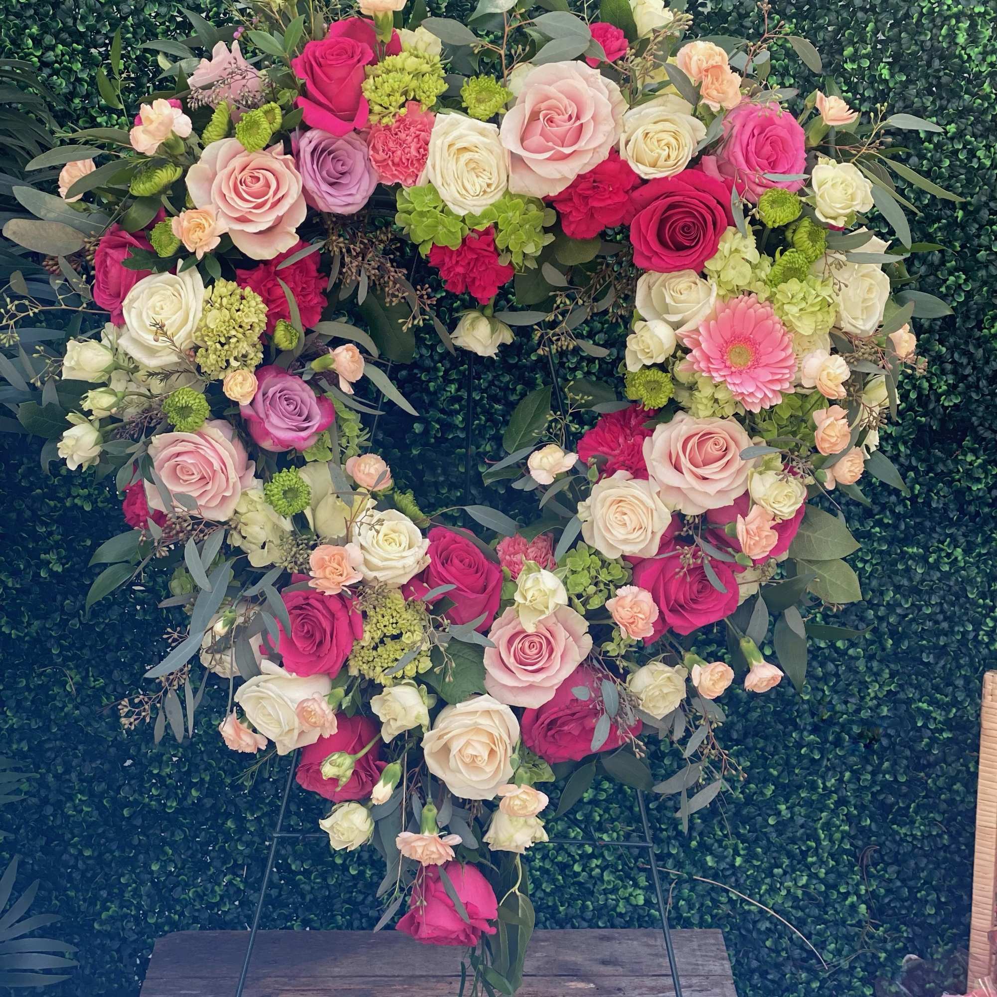 Heart-shaped floral wreath of pink, white, and peach roses