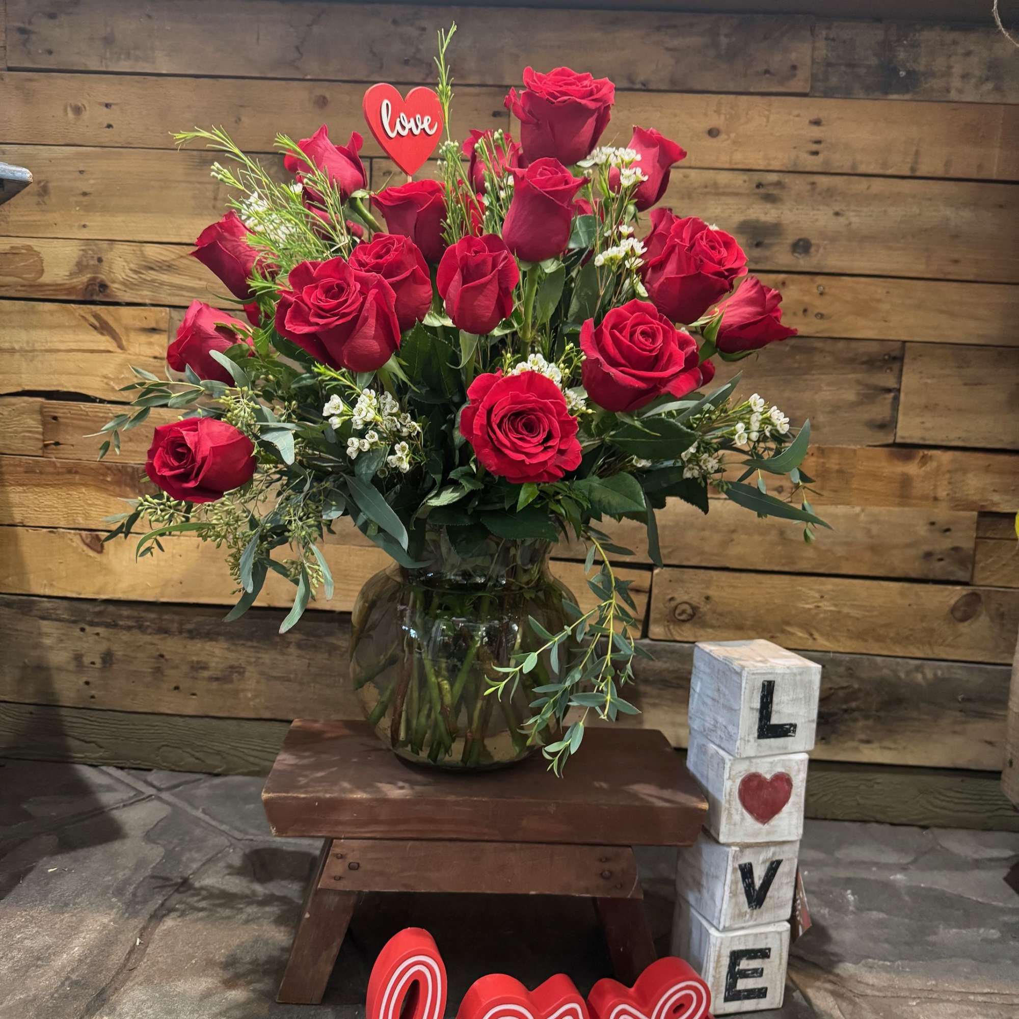 Red roses in a glass vase with love decorations