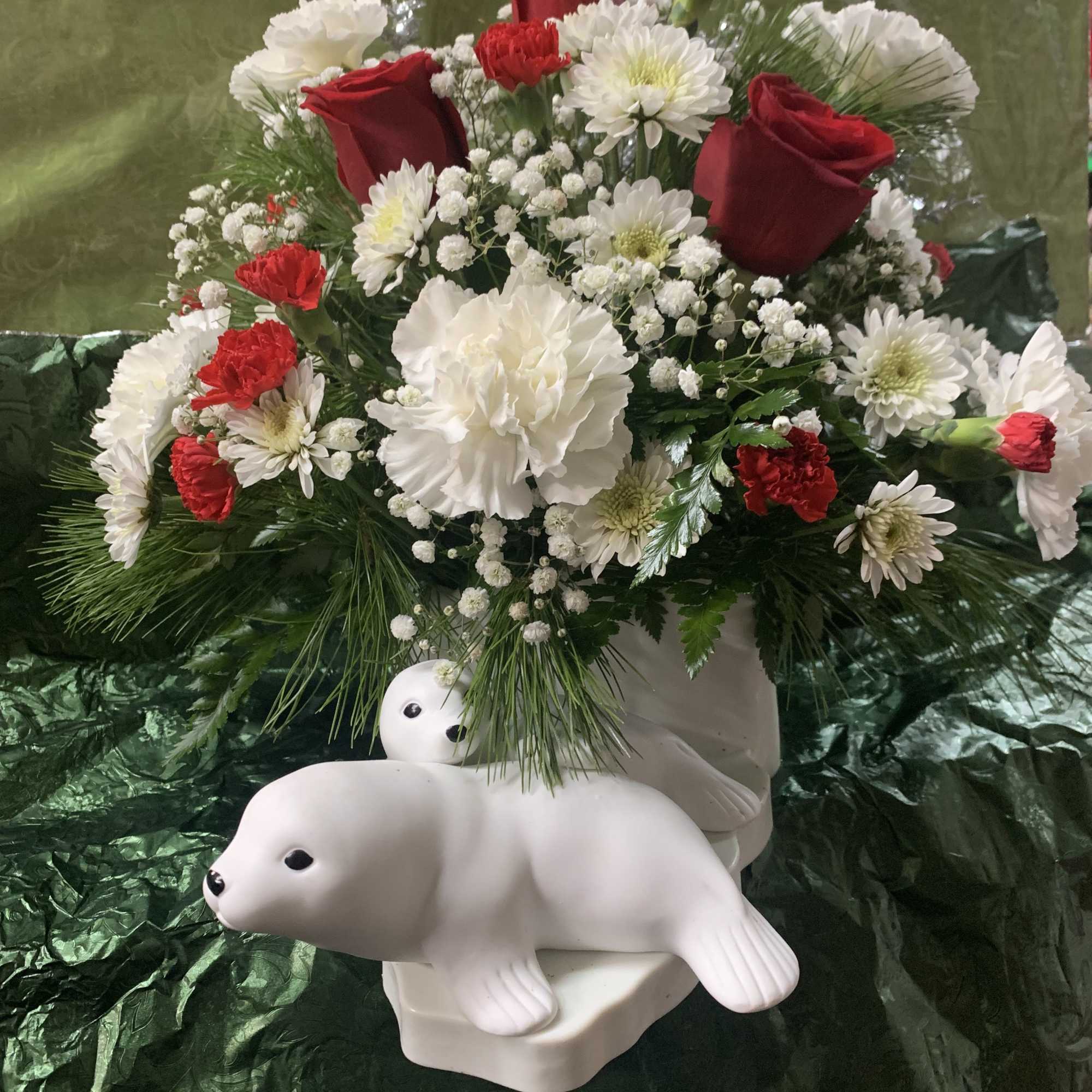 Red and white floral arrangement with two white seal figurines