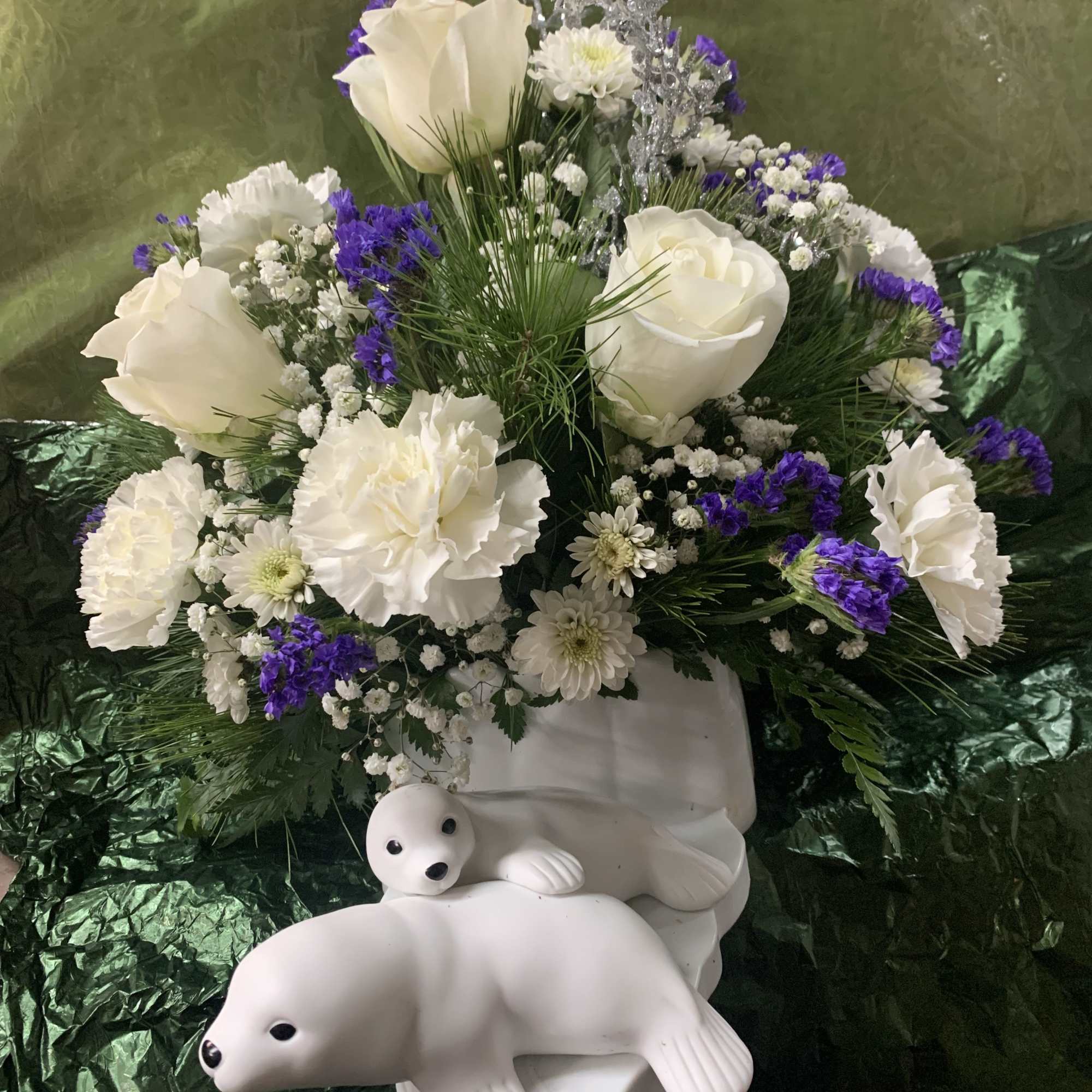 White roses and chrysanthemums with purple accents in a white polar bear vase