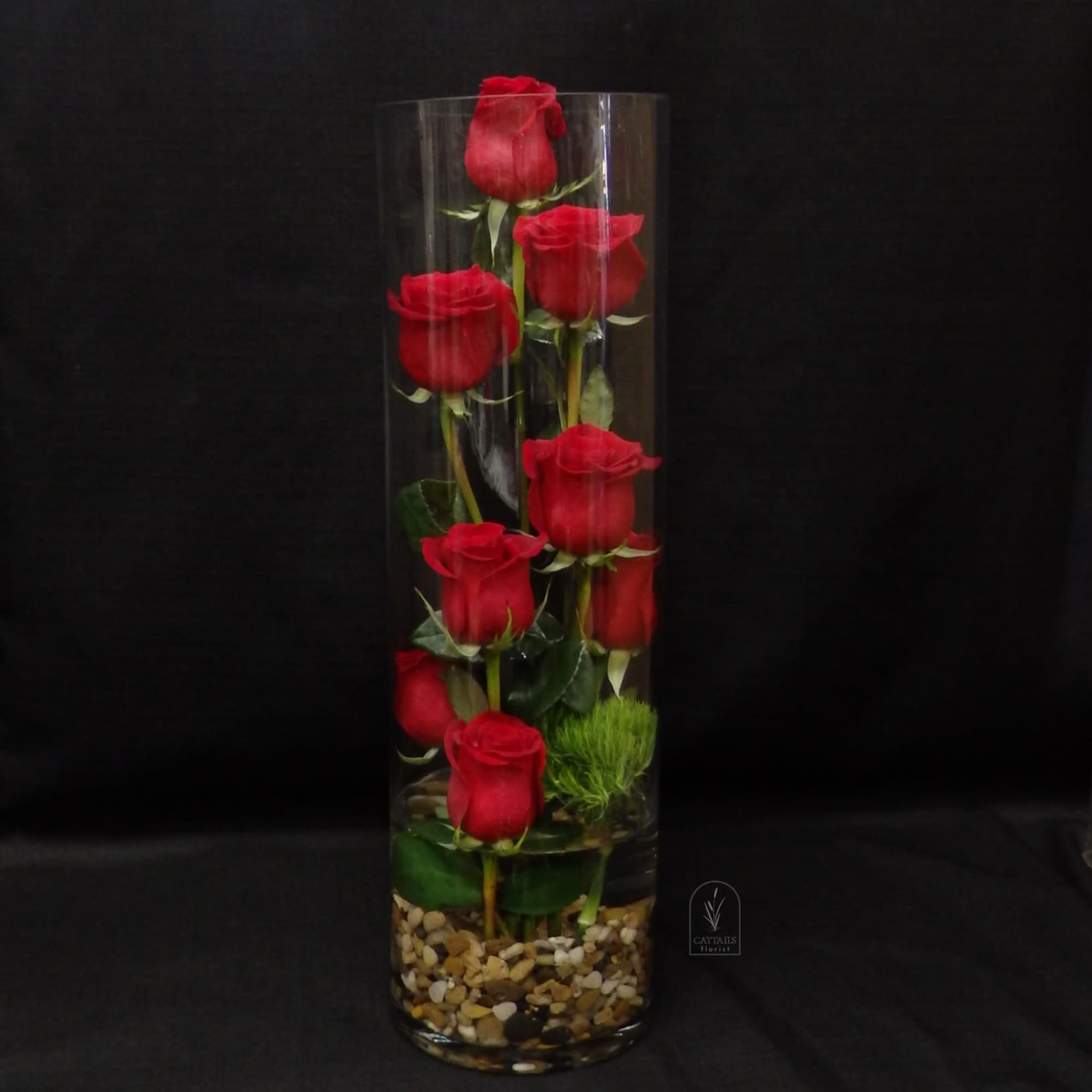 Tall glass vase with red roses arranged vertically