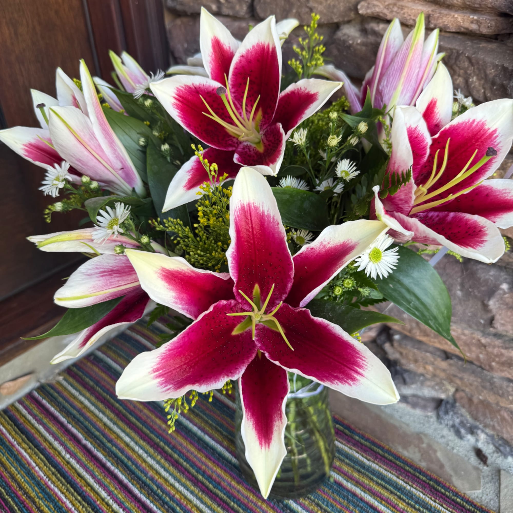 Pink-and-white lilies in a glass vase with small white daisies