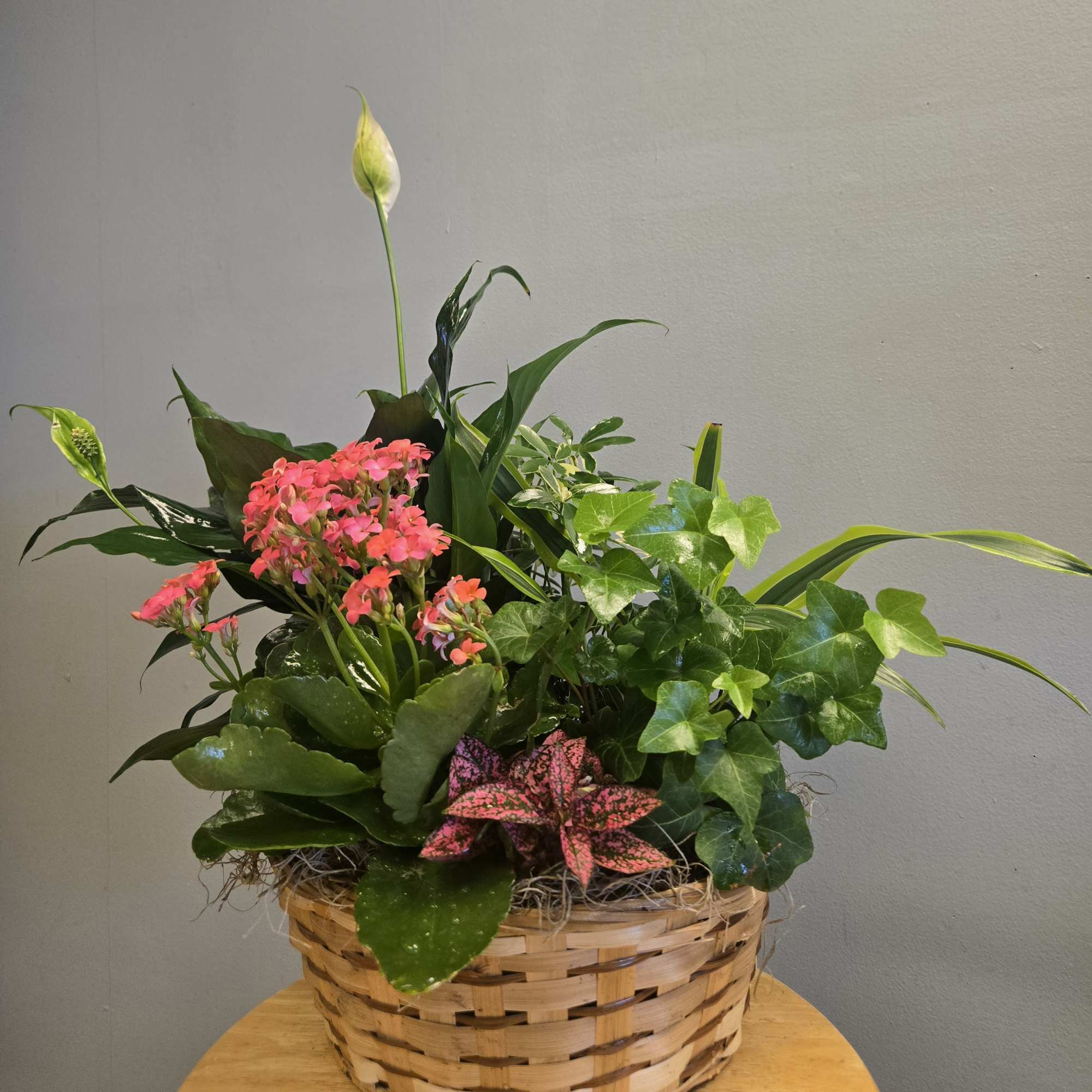 Mixed potted plants and pink flowers in a woven basket
