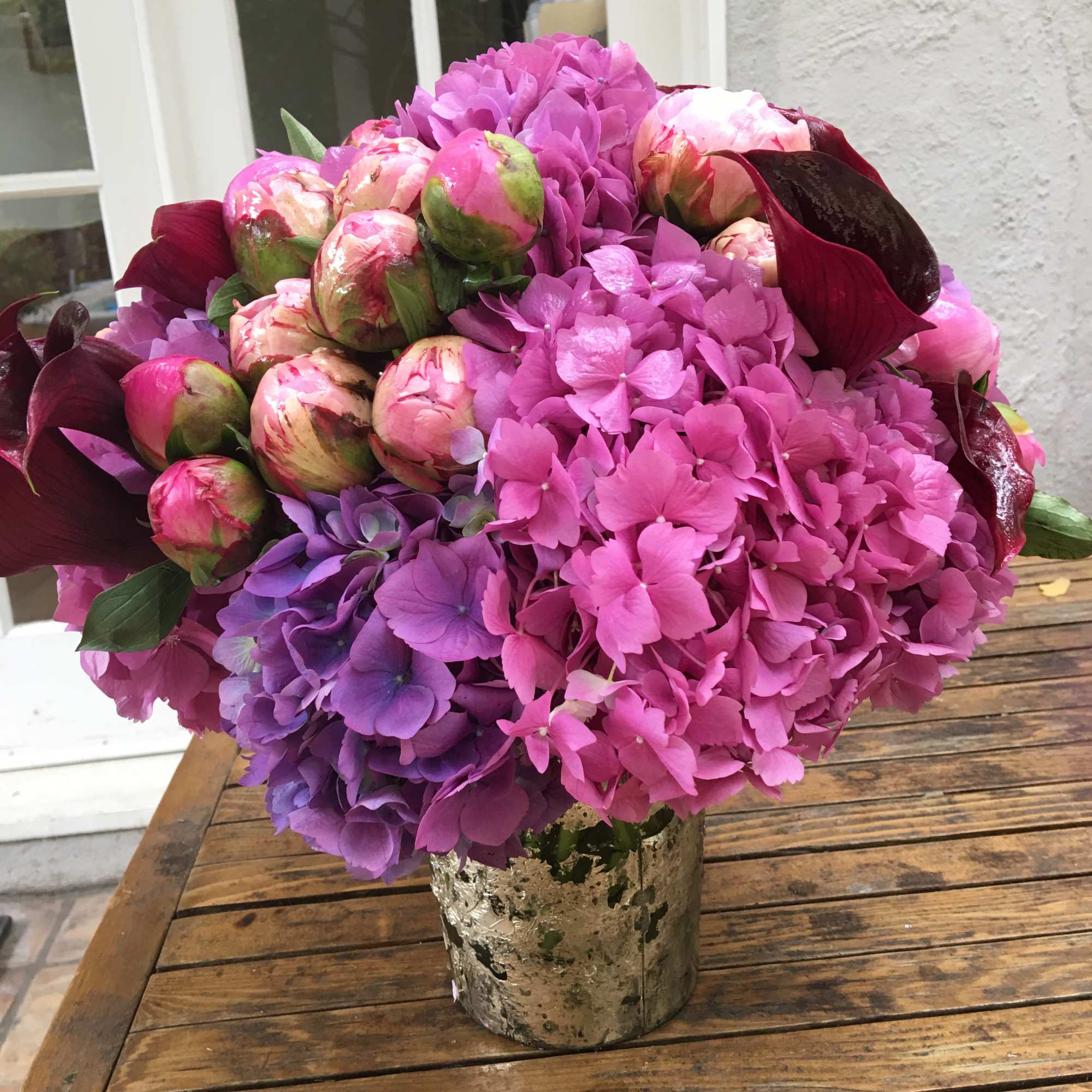 Pink and purple hydrangea bouquet with peonies in a metallic vase