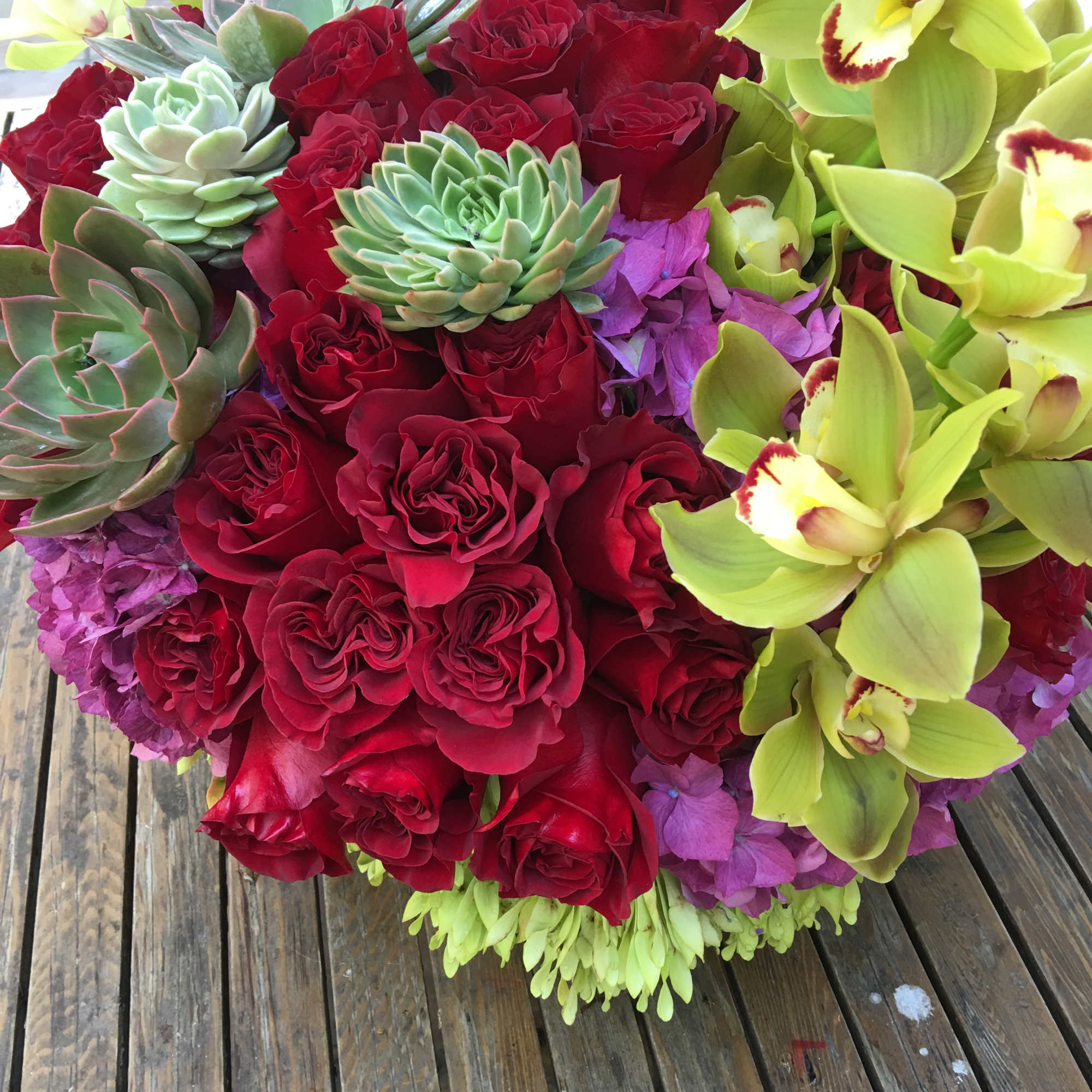 Bouquet of red roses, green orchids, and succulents