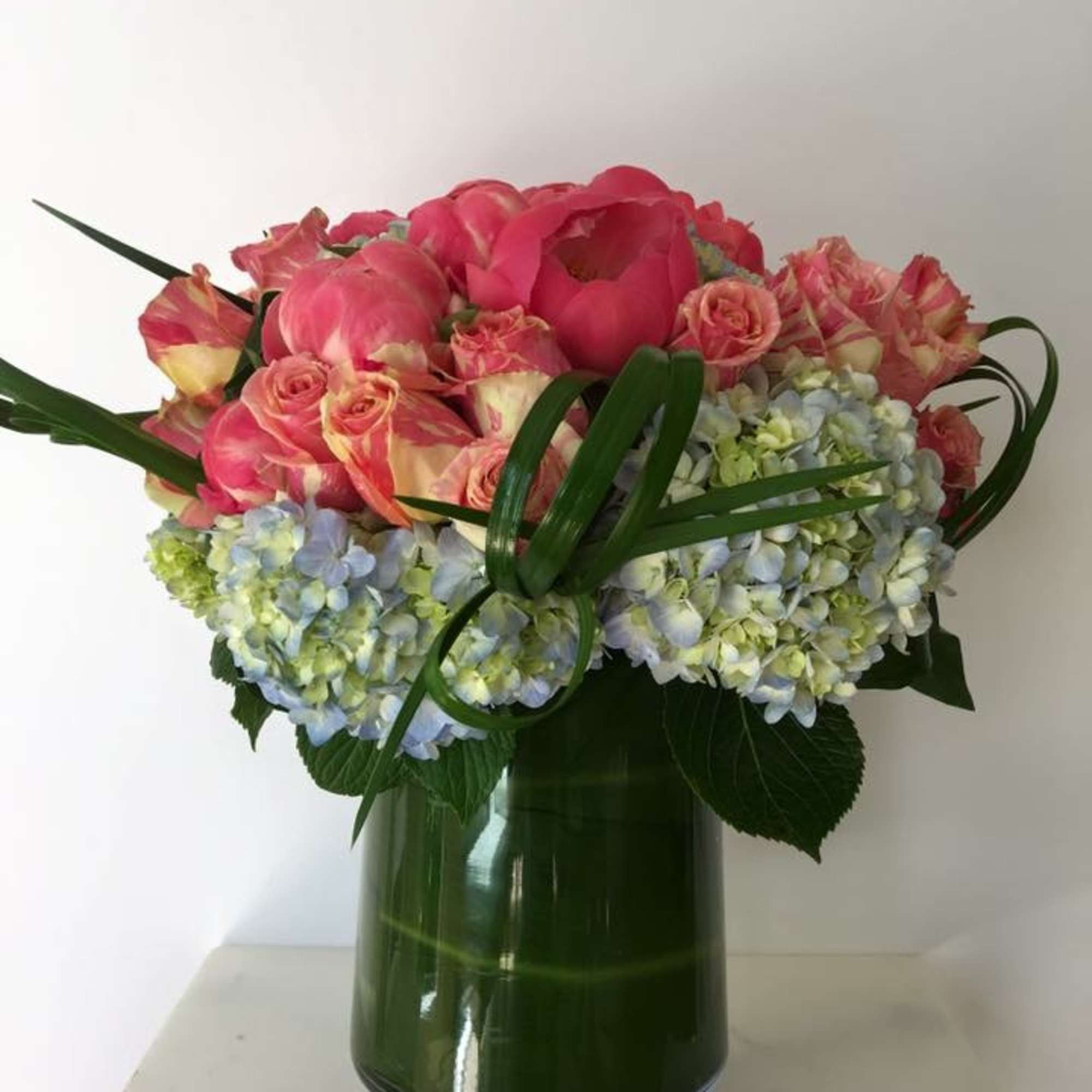 Pink roses and hydrangeas arranged in a green glass vase, photo 2 of 3