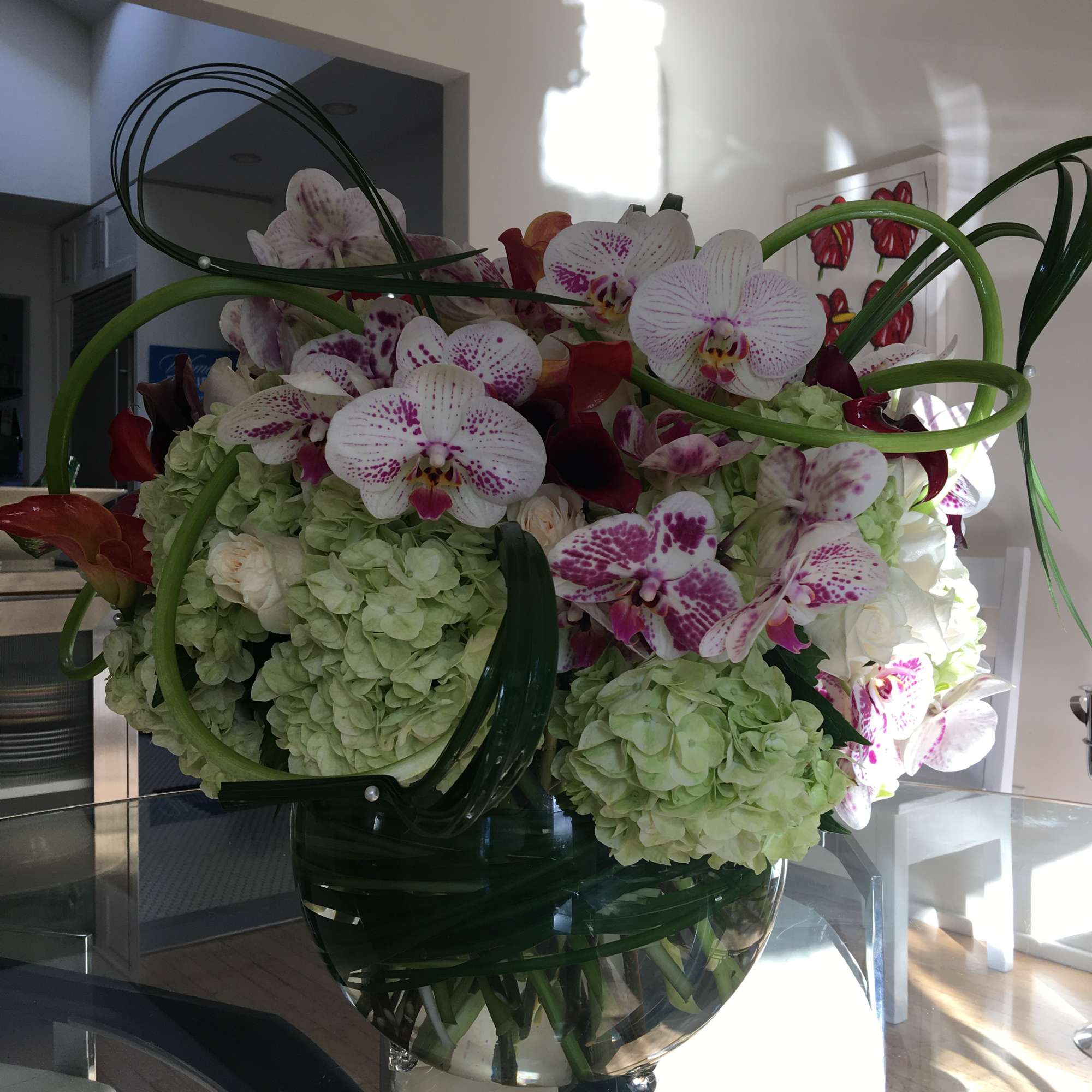 Large orchid and hydrangea arrangement in a glass vase