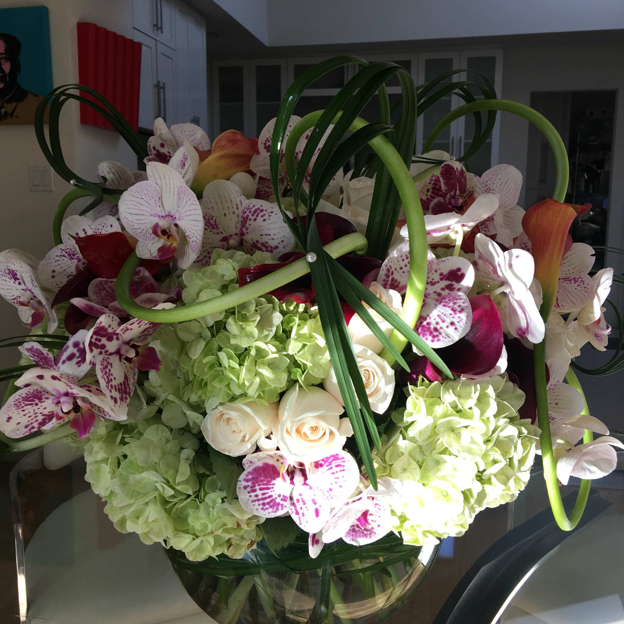 Large bouquet of orchids, roses, and hydrangeas in a glass vase