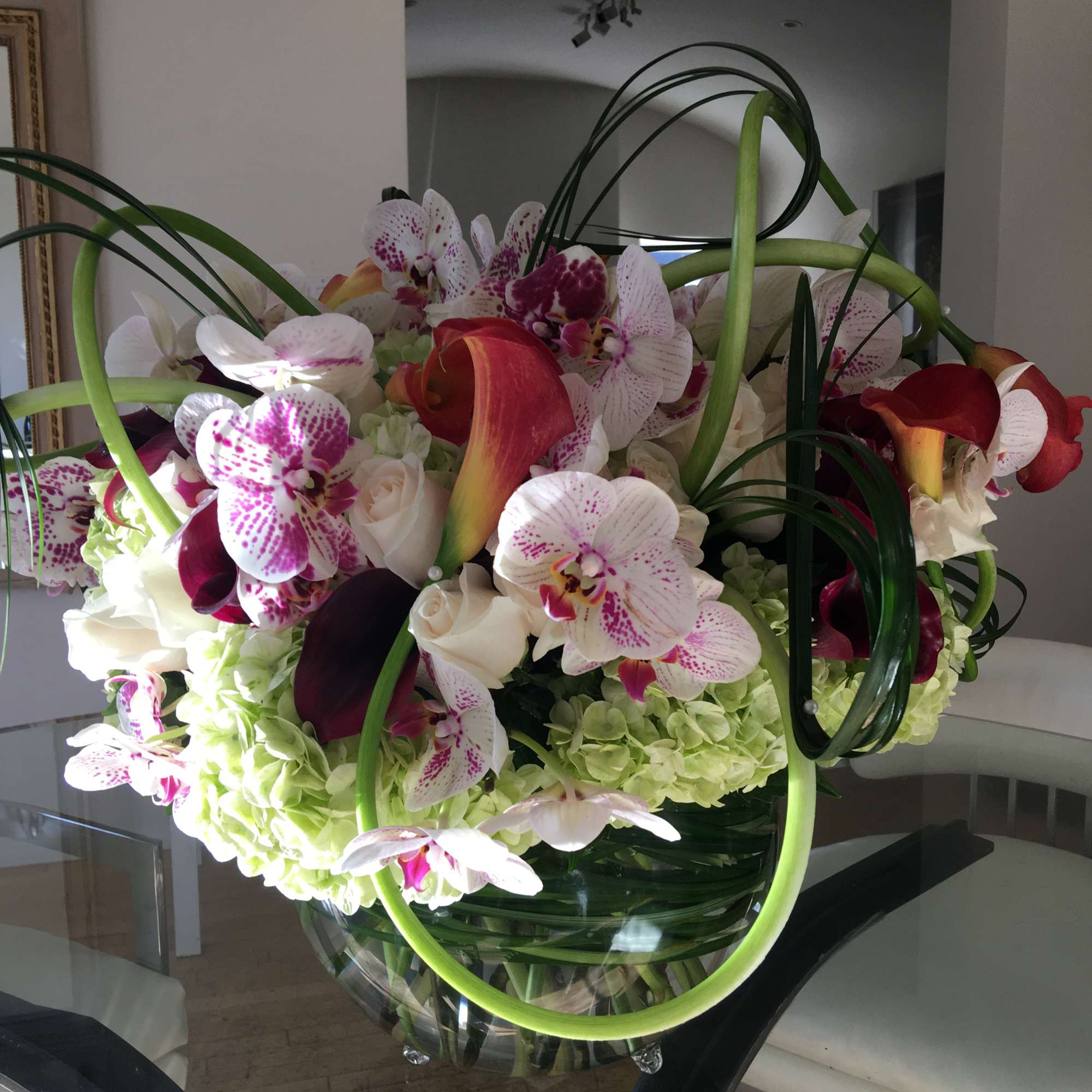 Large bouquet of orchids, calla lilies, and roses in a glass vase