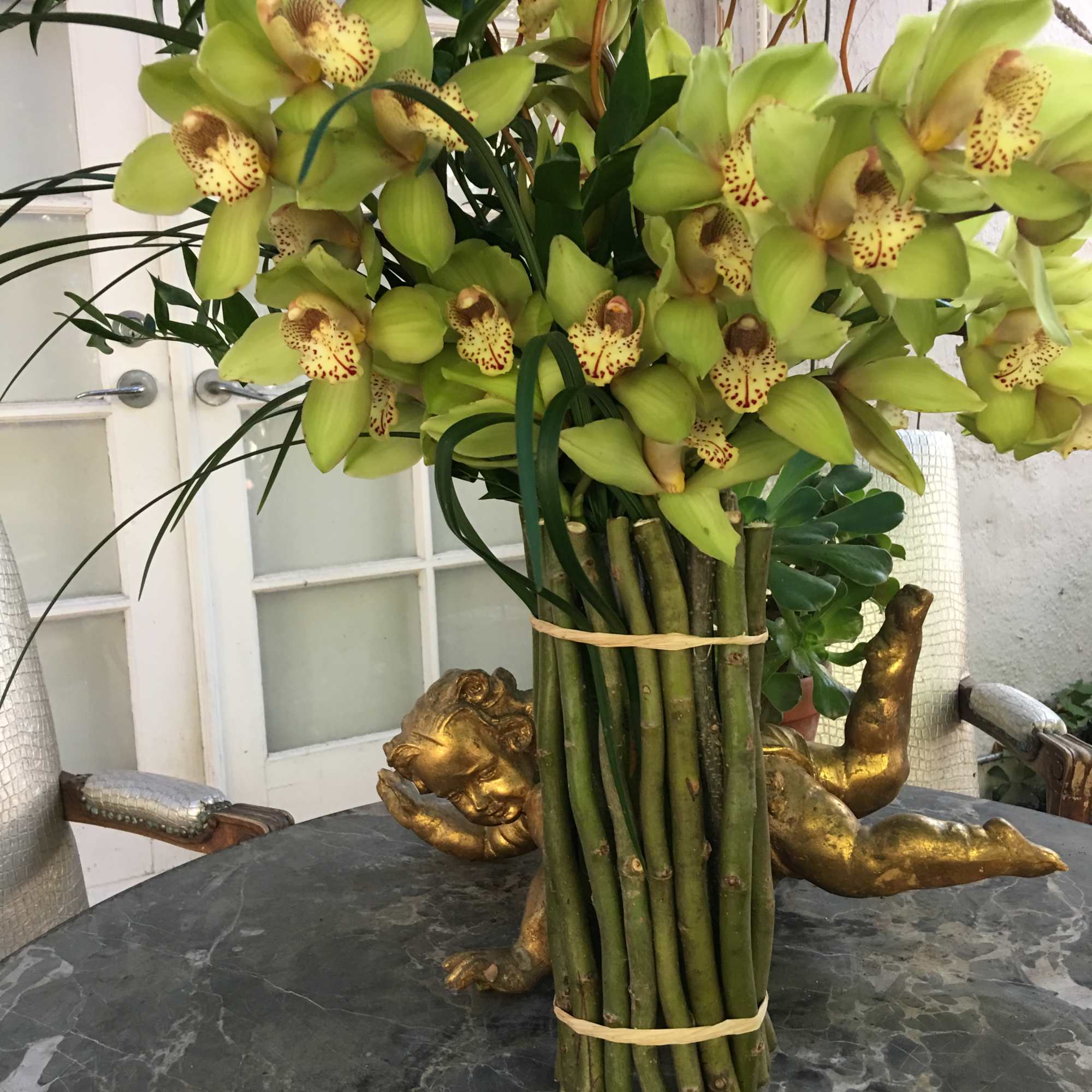 Green orchid arrangement in a tall vase on a table