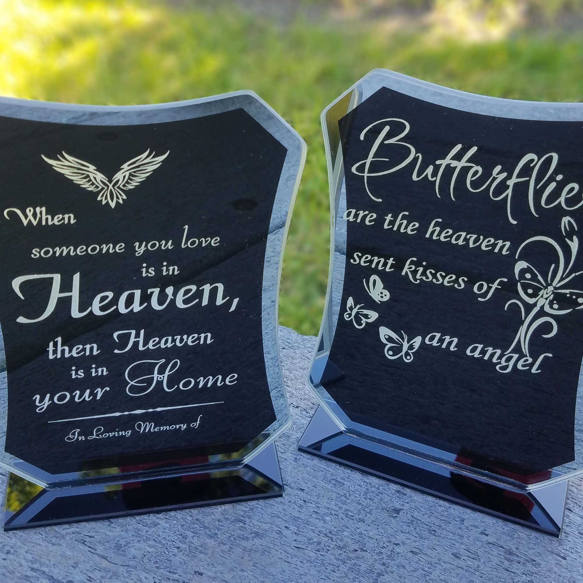 Two memorial plaques with butterfly and angel text on black acrylic stands