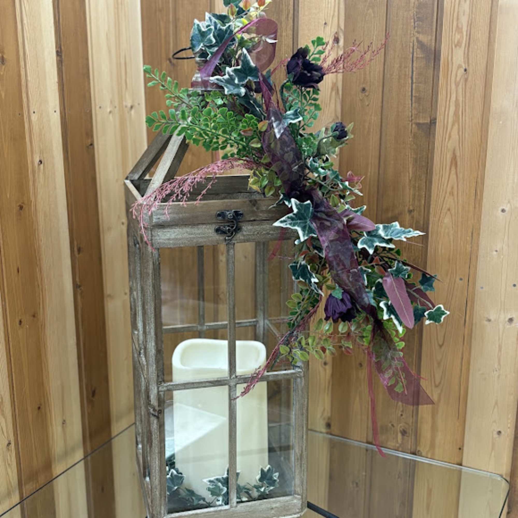 Decorative lantern with faux greenery and dark purple flowers