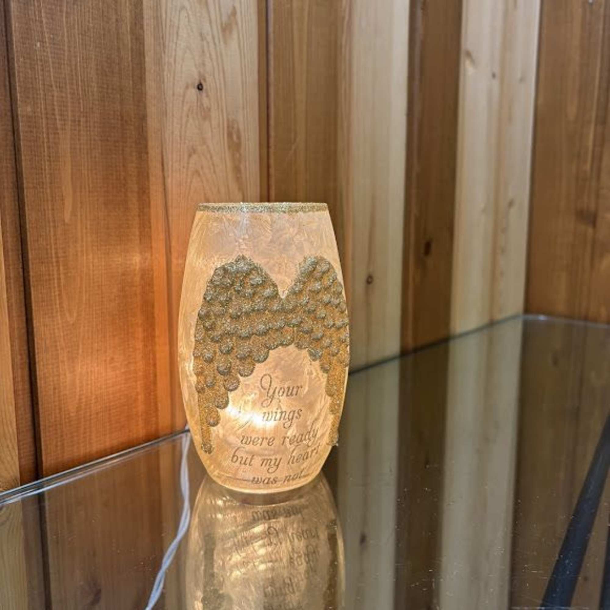 Lit memorial candle with angel wings and a sympathy message
